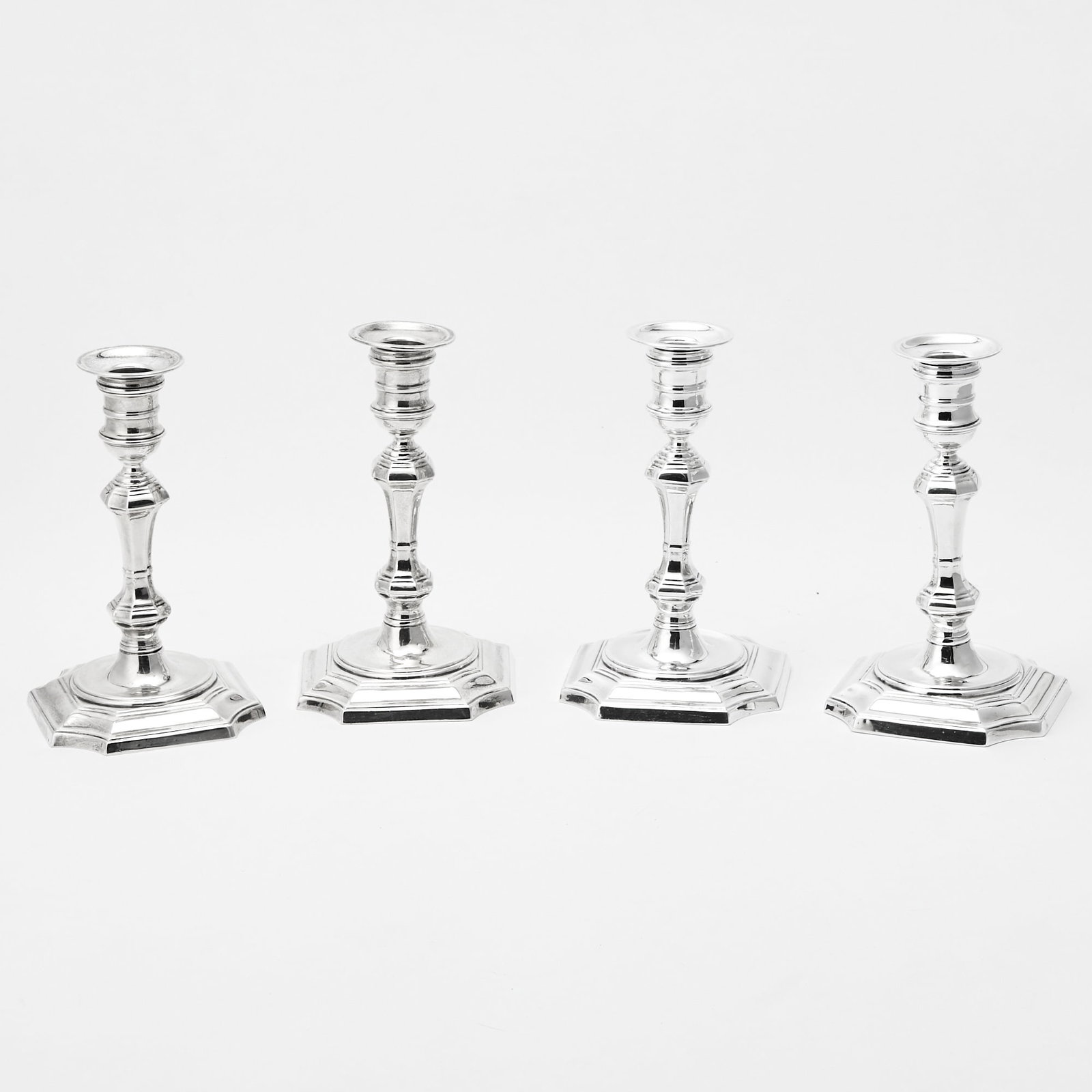 Set of Four American Sterling Silver Candlesticks: Peter Guille Ltd, New York, second quarter 20th century Each with a faceted knopped stem, on a square base with shaped corners. Height 7 1/2 inches, weighted.