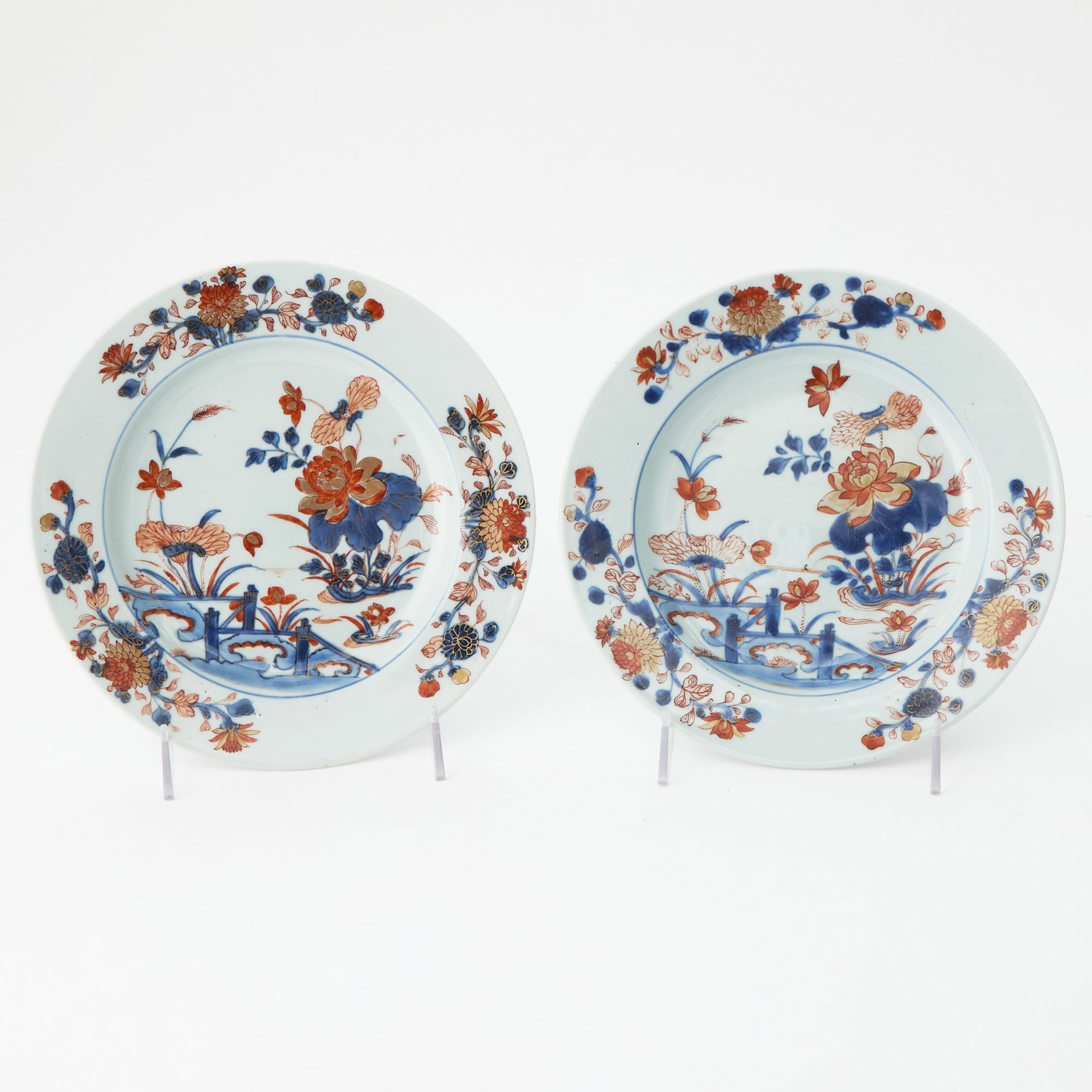 Two Chinese Export Porcelain Imari Plates: Mid-18th century Each center reserved a fenced garden with peonies and chrysanthemums issuing from rockwork within a floral spray border. Diameter 9 inches (22.8 cm). Provenance: Mark & Marjorie A