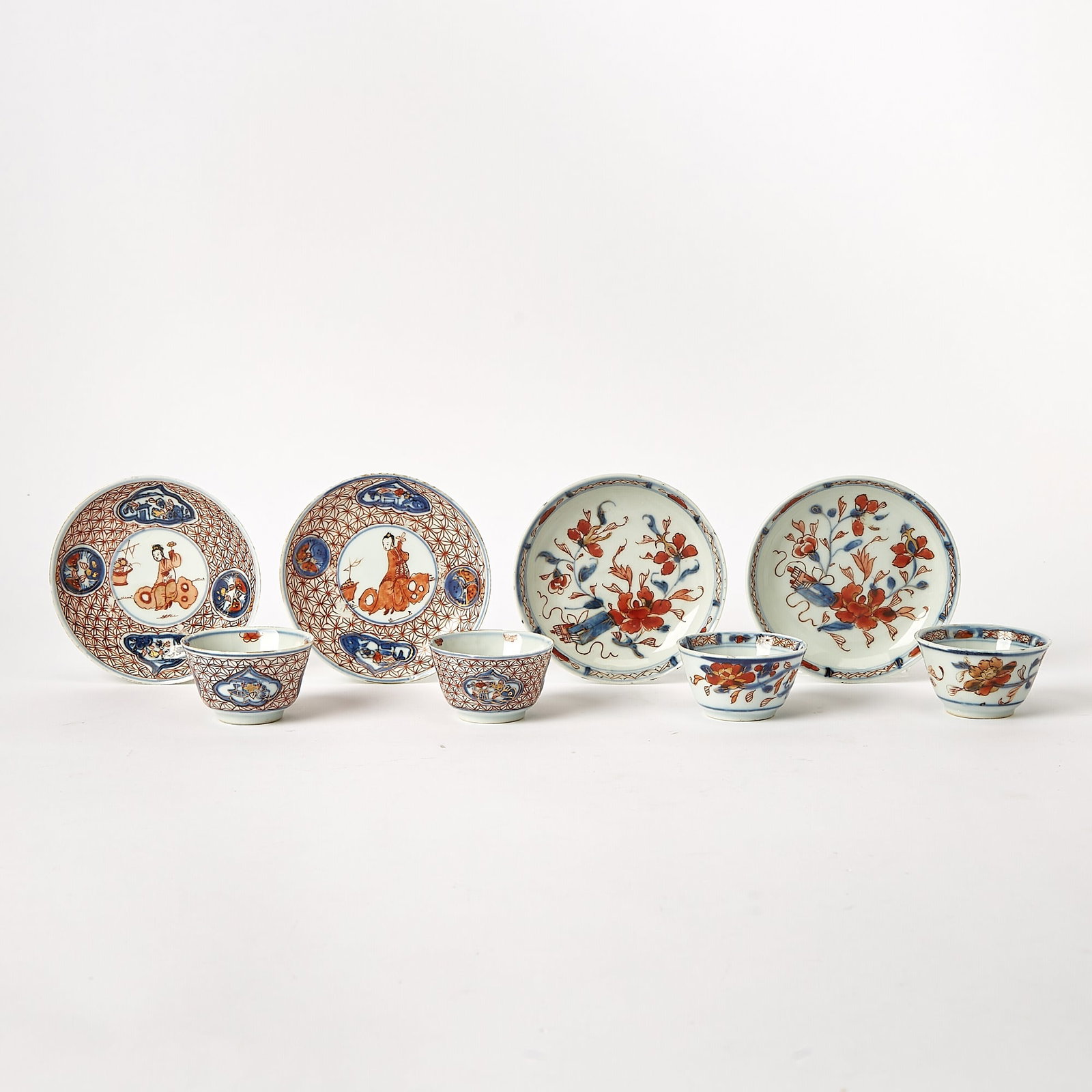 Group of Chinese Export Porcelain Imari Tea Bowls and Saucers: First half 18th century Comprising two pairs of tea bowls, the first with a prunus motif, the interior with diaper borders; the second, with cartouche landscapes interrupting a geometric iron-red grou