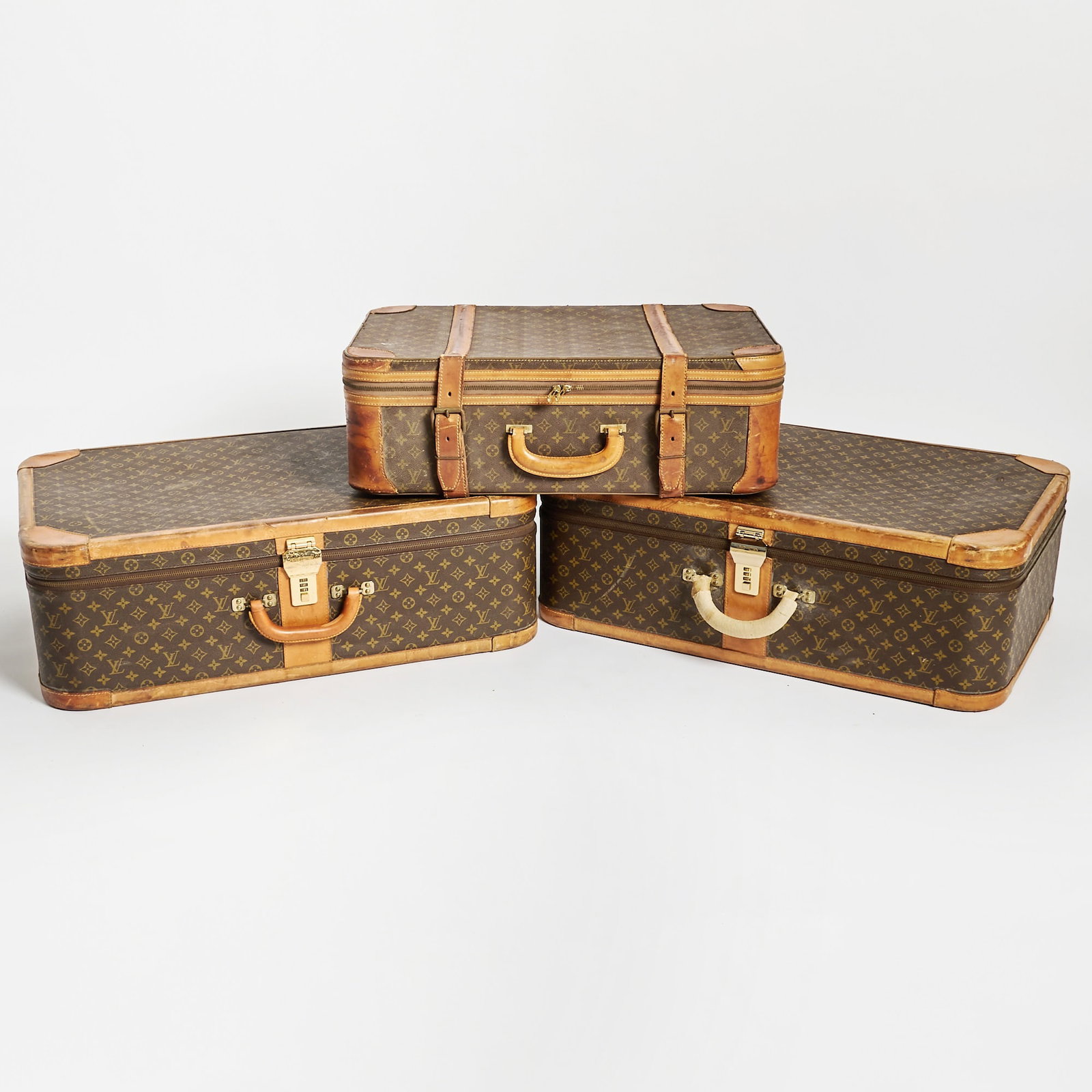 Three Louis Vuitton Suitcases: Height of two larger suitcases 31 inches, width 21 inches; height of small suitcase 27 inches, width 18 inches.