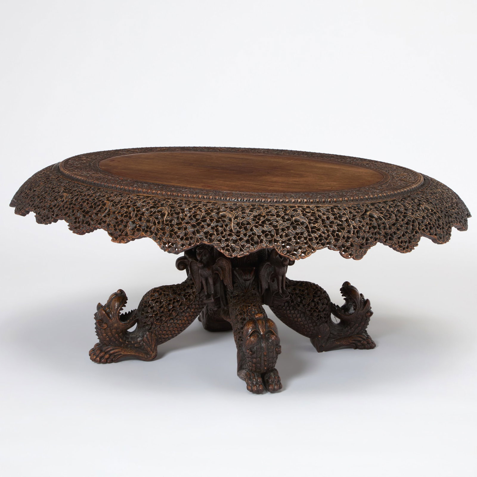 Southeast Asian Carved Hardwood Low Table: Probably Burmese, second half 19th century The circular top with a border carved with exotic animals and foliage, above a scalloped-pierced foliate frieze, raised on four lion feet headed by birds.