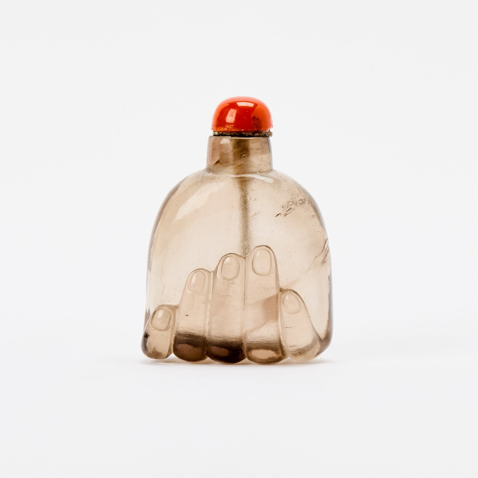 A Chinese Carved Smoky Crystal Snuff Bottle Qing Dynasty: Naturalistically carved in the form of a closed hand at the base. (Height 1 3/4 inches)