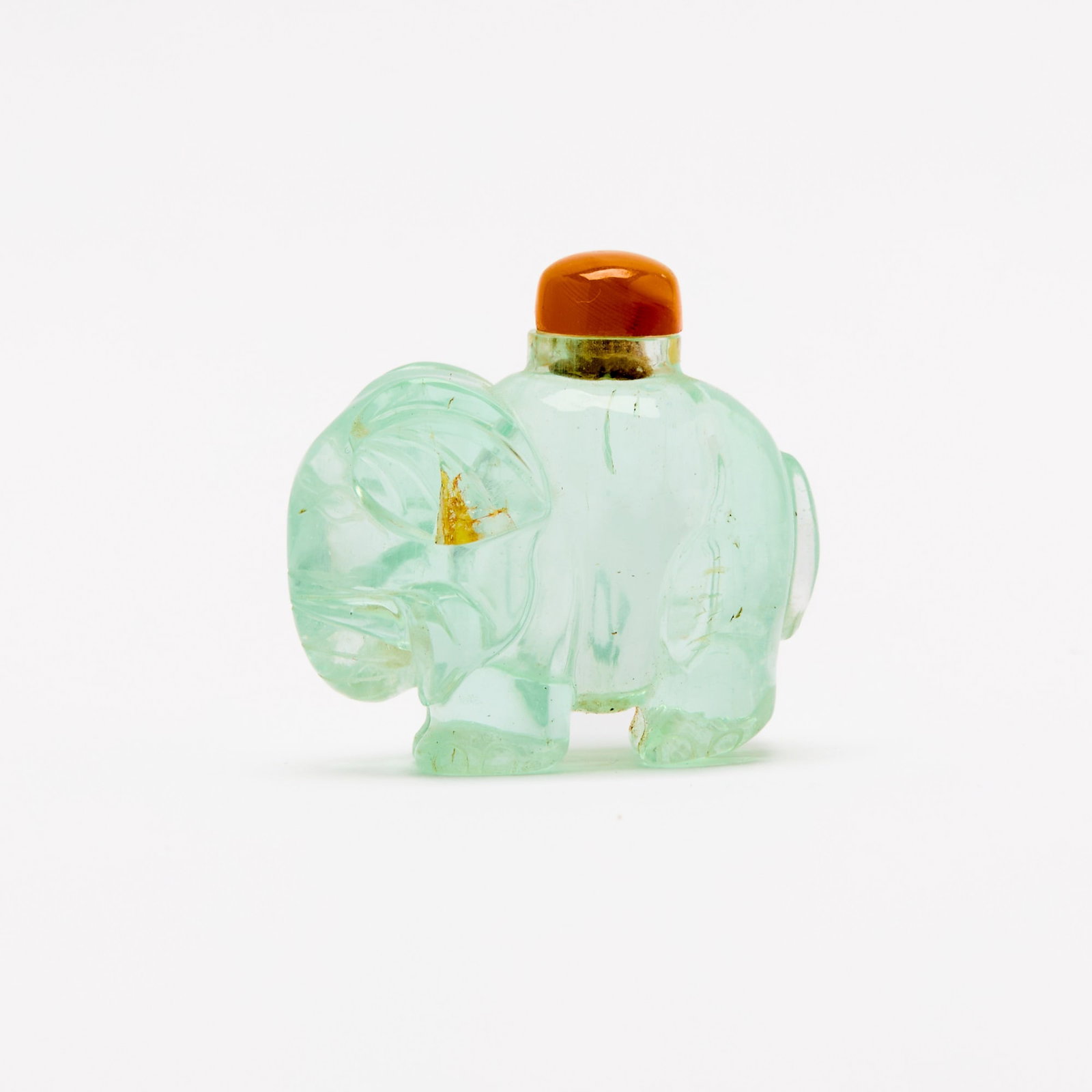 A Chinese Carved Aquamarine 'Elephant' Snuff Bottle Qing Dynasty: The standing figure with its head lowered and trunk coiled to one side, surmounted by an agate stopper. (Width 2 1/2 inches)