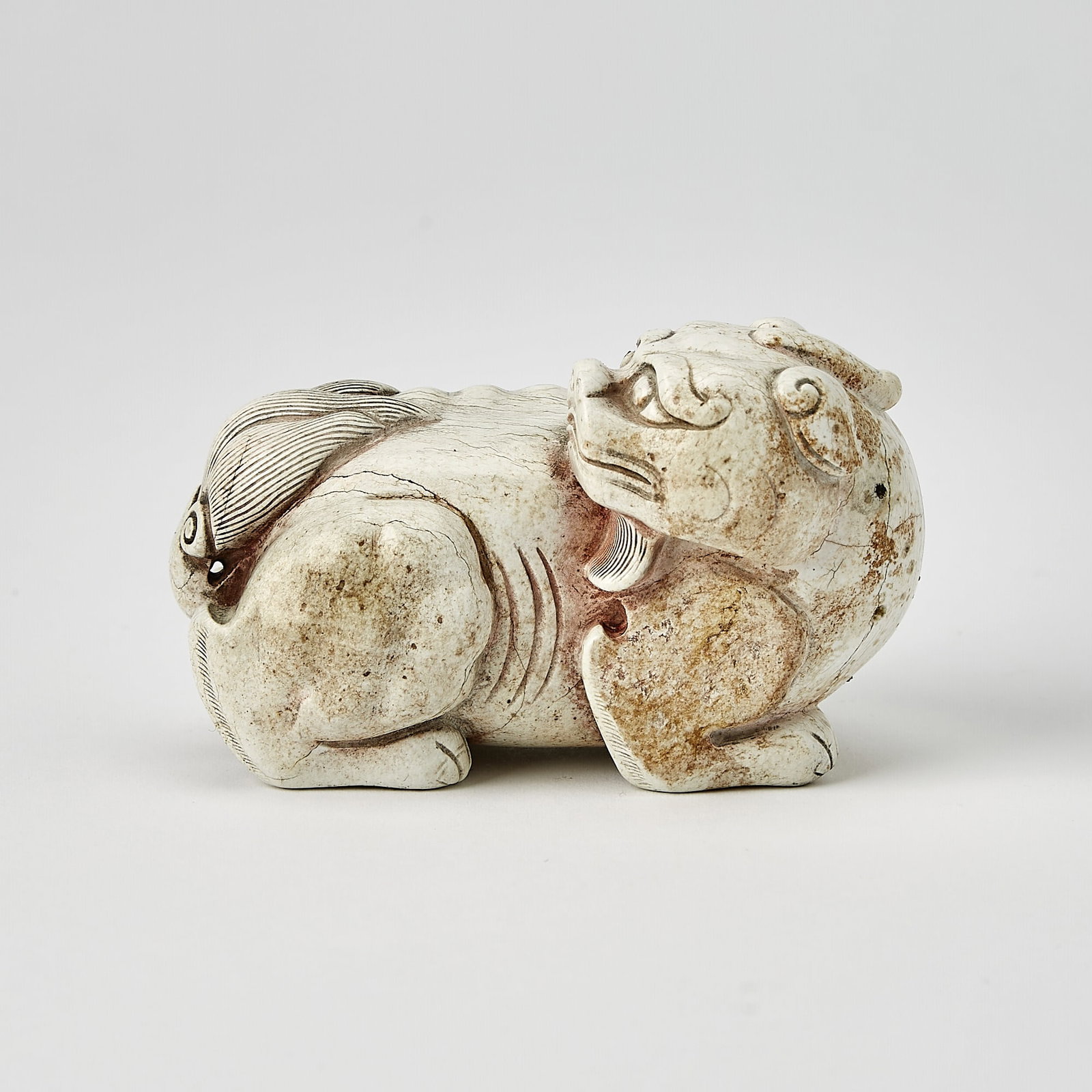 A Chinese Carved Jade Recumbent Qilin Ming-Qing Dynasty: The mythical beast with its head turned backward, gazing over its back. (Length 4 inches)