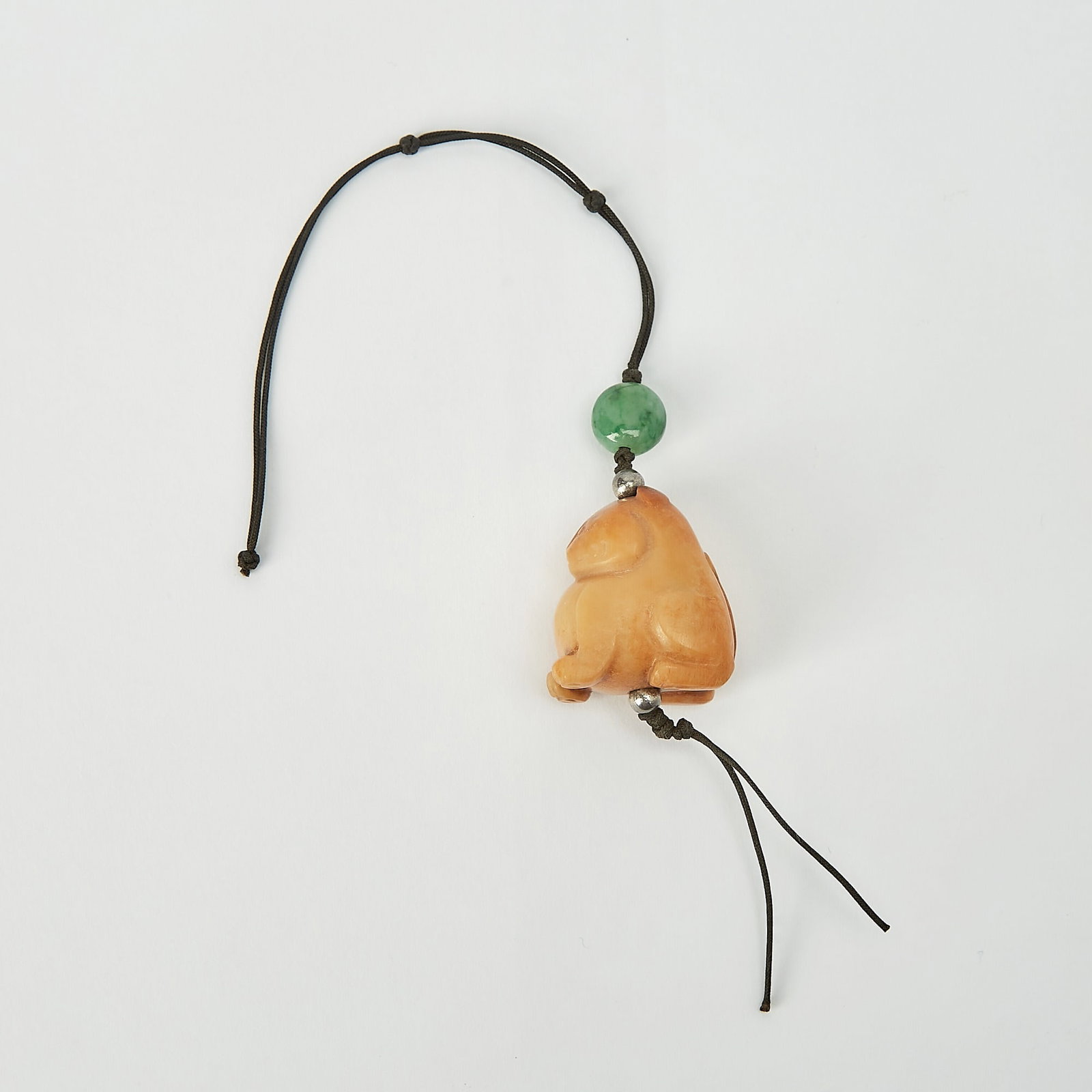A Chinese Jade Tiger Pendant Ming-Early Qing Dynasty: Carved as a tiger seated on its haunches, the jade of mottled russet coloring. (Length 2 inches)