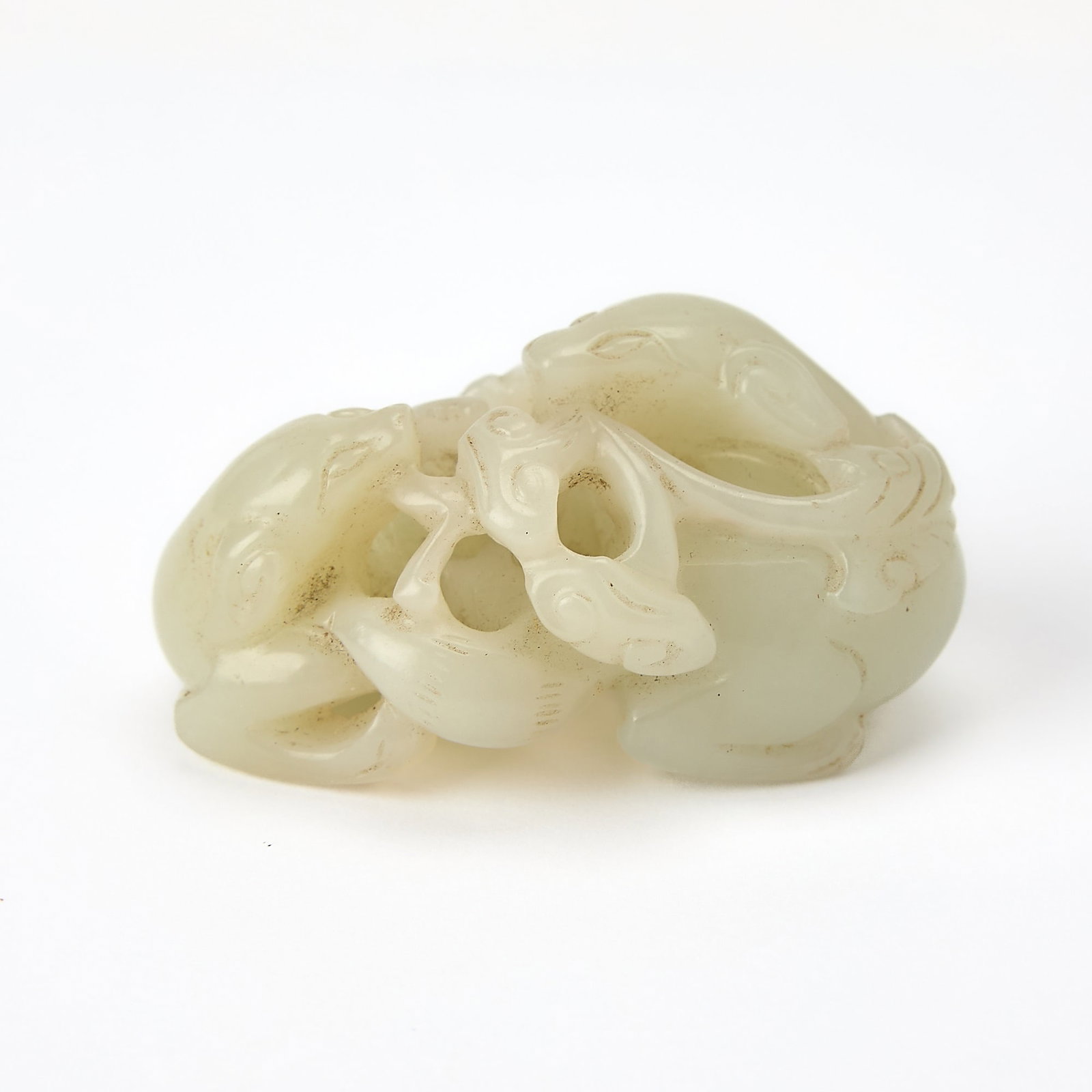 A Chinese Pale Celadon Jade Figural Group Qing Dynasty: Carved as a pair of confronting beasts holding a stem of lingzhi in their mouths. (Length 2 inches)