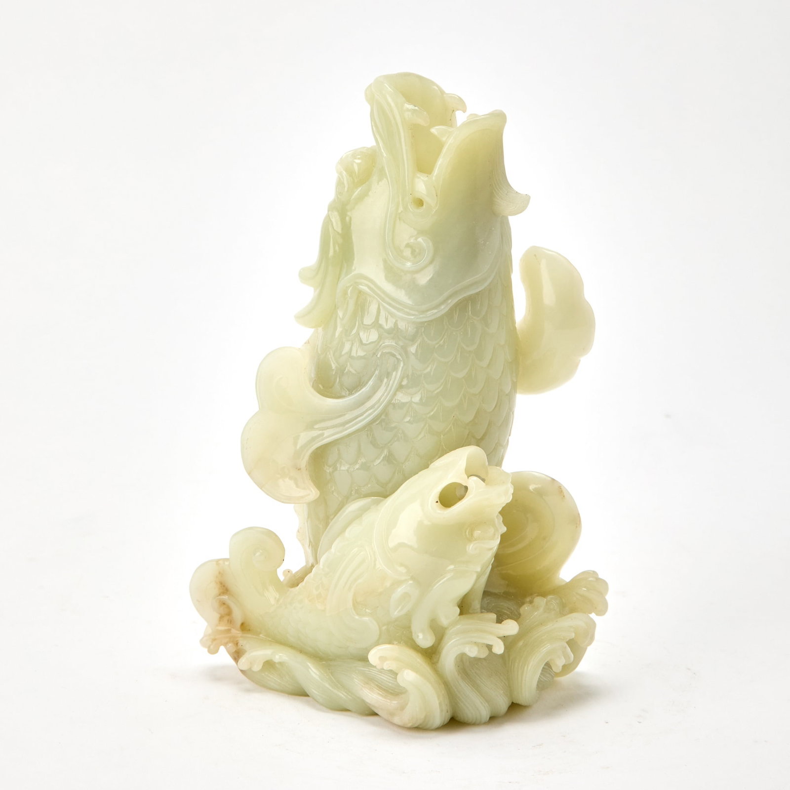A Chinese Celadon Jade Carving of a Figural Group 18th-19th Century: Carved as an upright carp emerging from crashing waves, accompanied by a smaller carp. (Height 9 1/4 inches)
