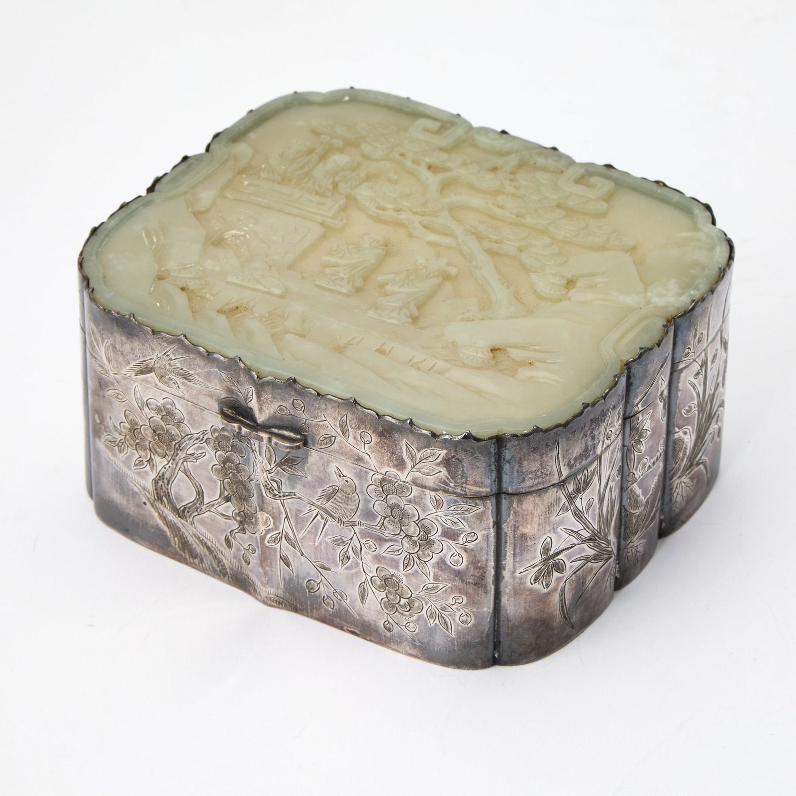 A Chinese Engraved Silver Box and a Celadon-Jade-Inset Cover 2nd Half of 19th Century: Of rectangular form; the exterior decorated with blossoming branches; the jade inset carved with figures under a pine tree, all within a mountainous landscape. (Length 5 1/2 inches)