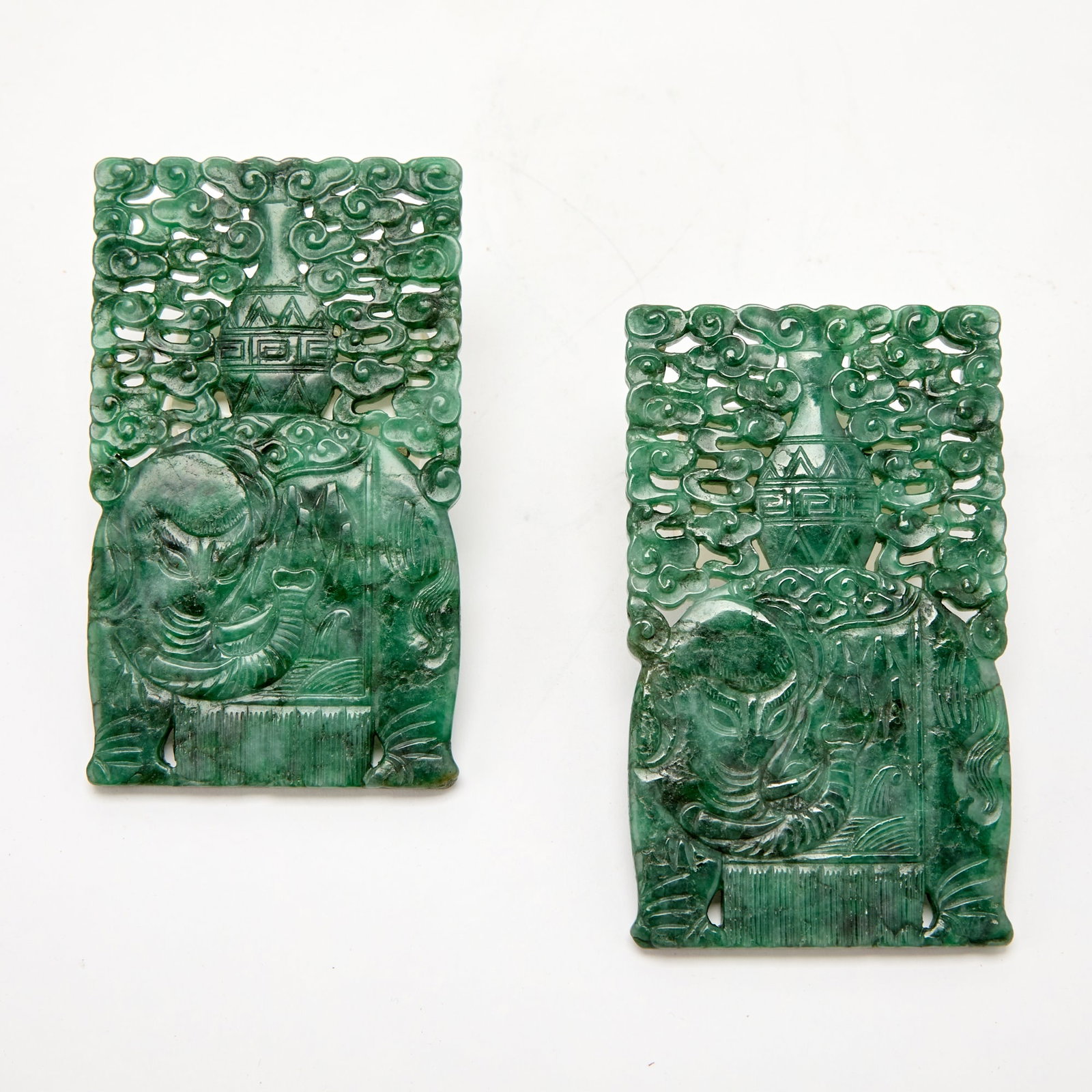A Pair of Chinese Carved Chloromelanite Jadeite Plaques Republic Period: Each carved in openwork with an elephant carrying a vase on its back beneath swirling clouds. (Length 4 3/4 inches)