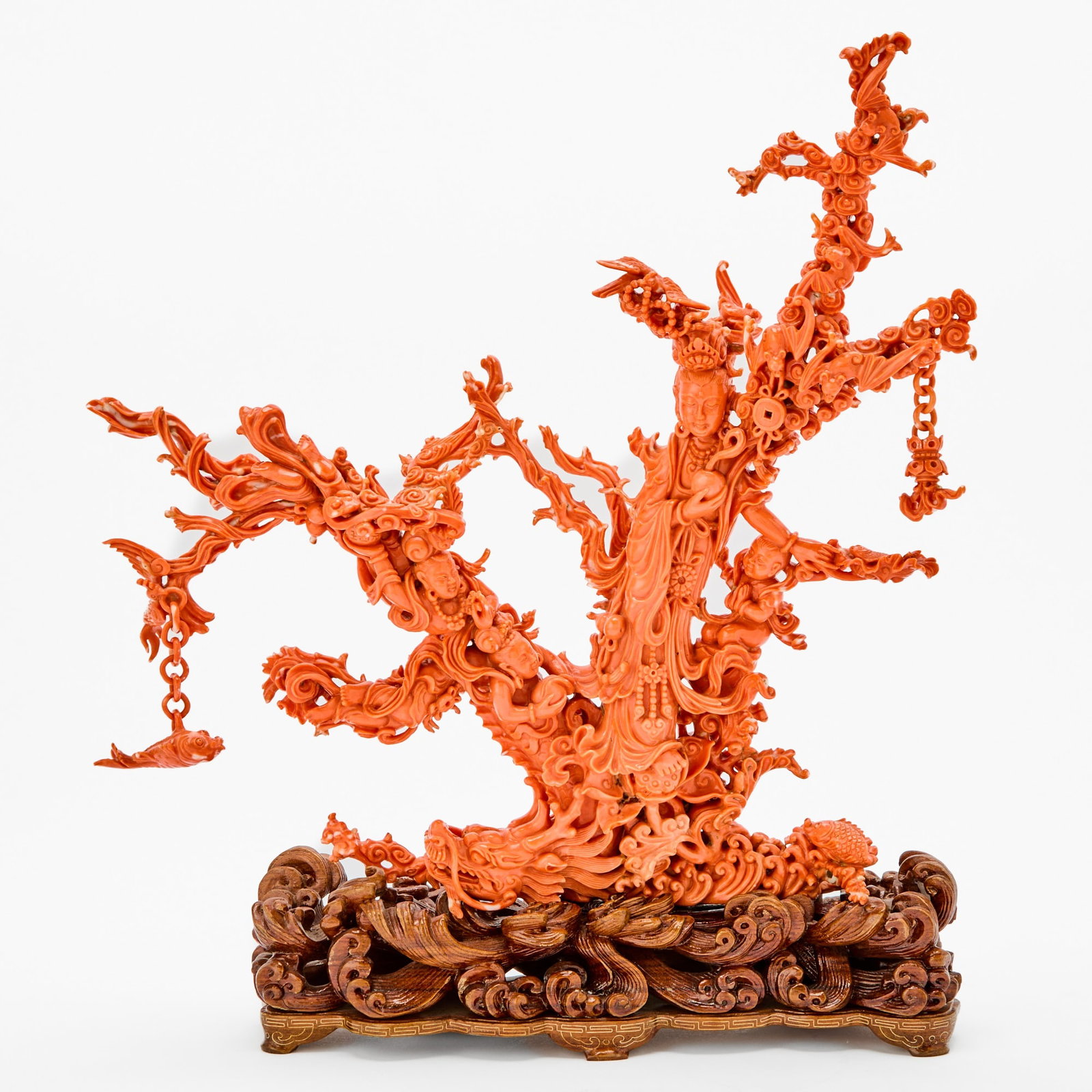 A Chinese Coral Carving of a Figural Group Date 1978: Extensively carved with Guanyin standing amid swirling waves and cloud scrolls, dressed in long flowing robes and accompanied by a boy attendant and celestial maidens, with a dragon, fu bats, and carp