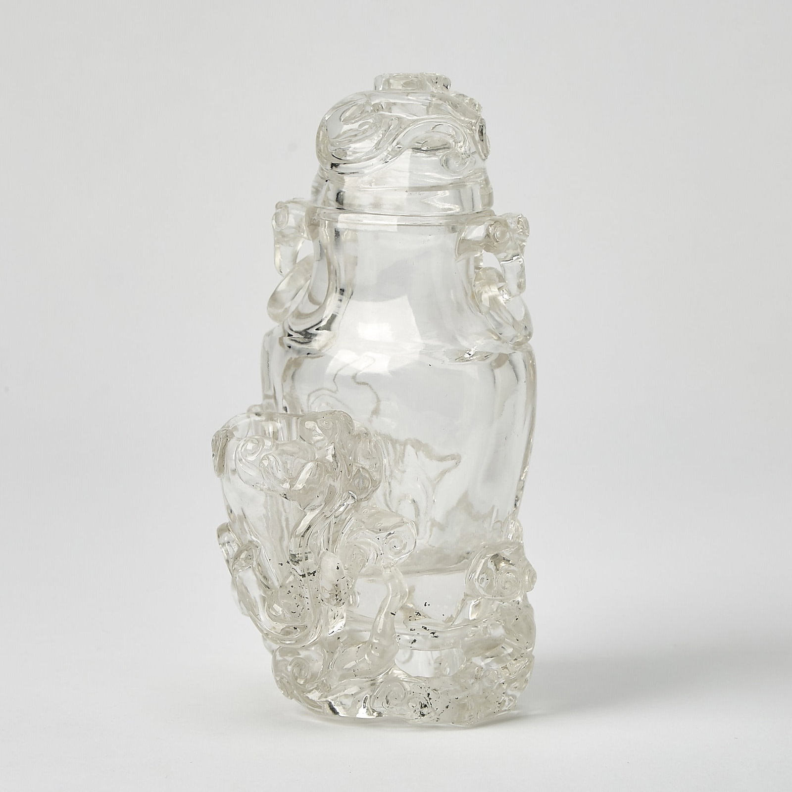 A Chinese Rock Crystal Vase Qing Dynasty: Carved as a flattened vase form, encircled by mythical beasts and lingzhi stems. (Height 7 inches)
