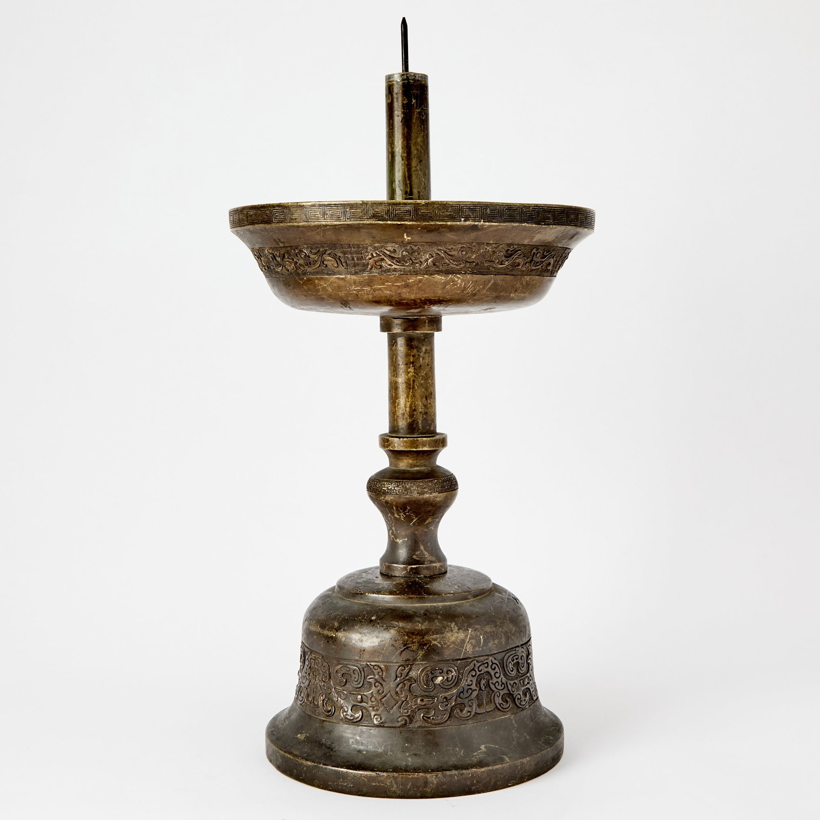 A Large Chinese Cast Bronze Temple Candle Holder Early Qing Dynasty: The domed base cast with archaistic band incorporating taotie masks and supporting a vasiform and cylindrical stem; the wide cup-like receptical similarly decorated with archaistic band and greek key 