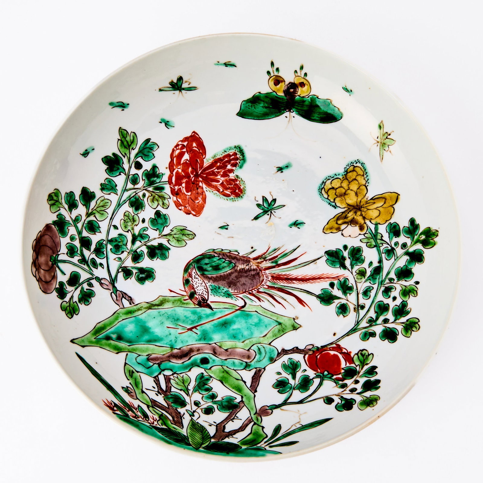 A Chinese Famille Verte Porcelain Dish Kangxi Period: Decorated with a phoenix perched on rockwork, surrounded by blossoming branches and butterflies. (Diameter 9 inches)