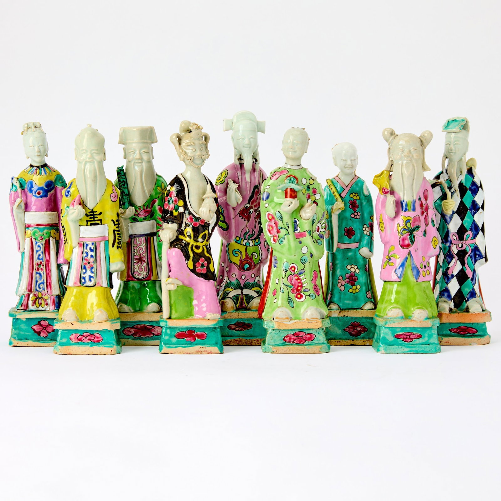 A Group of Nine Chinese Famille Rose Porcelain Figures of Immortals Early 19th Century: Each modeled standing atop a rectangular plinth, dressed in long robes and holding their respective attributes. (Height 9 1/2 inches)