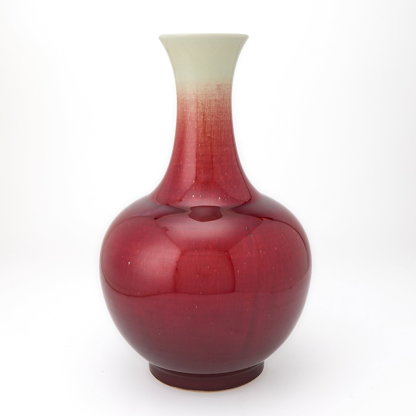 A Chinese Copper Red Glazed Porcelain Bottle Vase 19th Century: The exterior covered in a lustrous crushed-strawberry glaze, thinning to a milky tone at the mouth. (Height 15 1/4 inches)