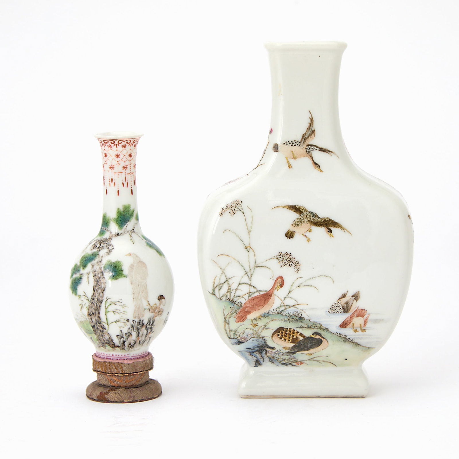 Two Small Chinese Famille Rose Porcelain Vases Apocryphal Qianlong Marks, Republic Period: Comprising a compressed square-section vase decorated with geese in and along a river with rocks and reeds, and a small bottle vase decorated with a hawk perched upon a rock under a pine tree. (Height