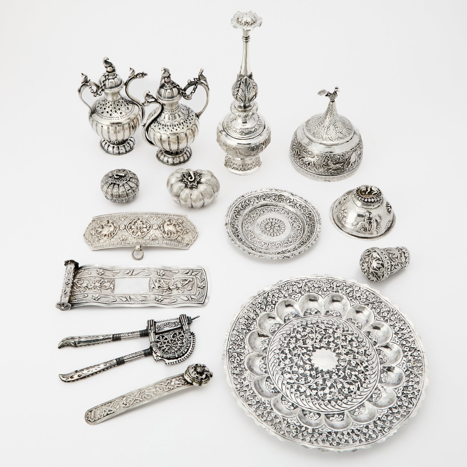 Assorted Group of Indian, Chinese, and Southeast Asian Silver and Silvered Metal Articles 19th-20th: Comprising two floral patterned dishes, the larger with pierced rim; two diminutive melon-form boxes and covers; a rose water sprinkler with narrow neck; a box and cover with peacock finial; a betel n