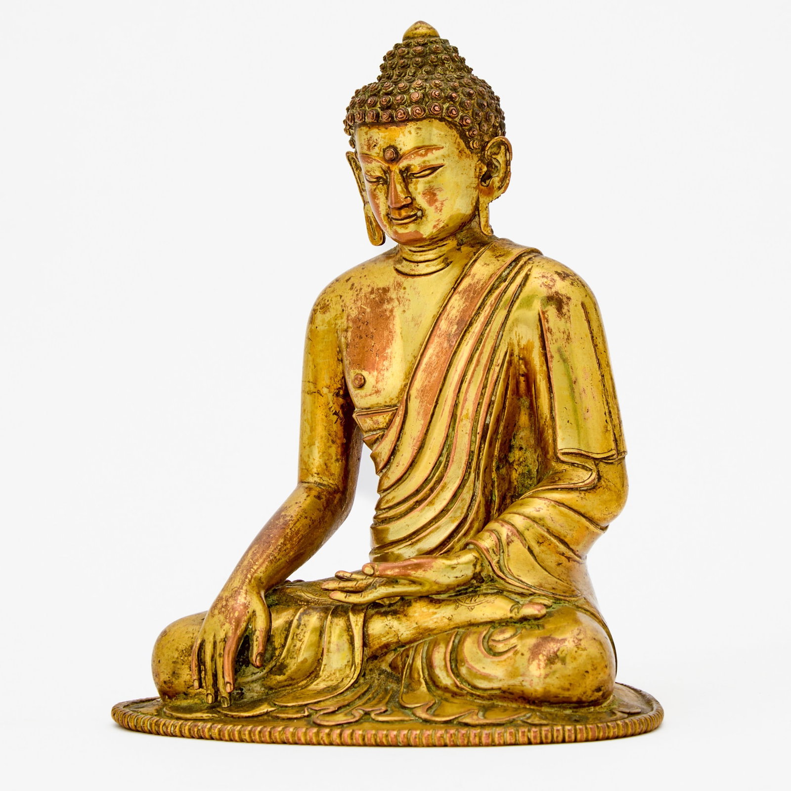 A Tibeto-Chinese Gilt Copper Alloy Figure of Shakyamuni 18th century: Of typical depiction, seated in dhyanasana and adorned in simple, loose robes; sans base. (Height 6 1/2 inches)