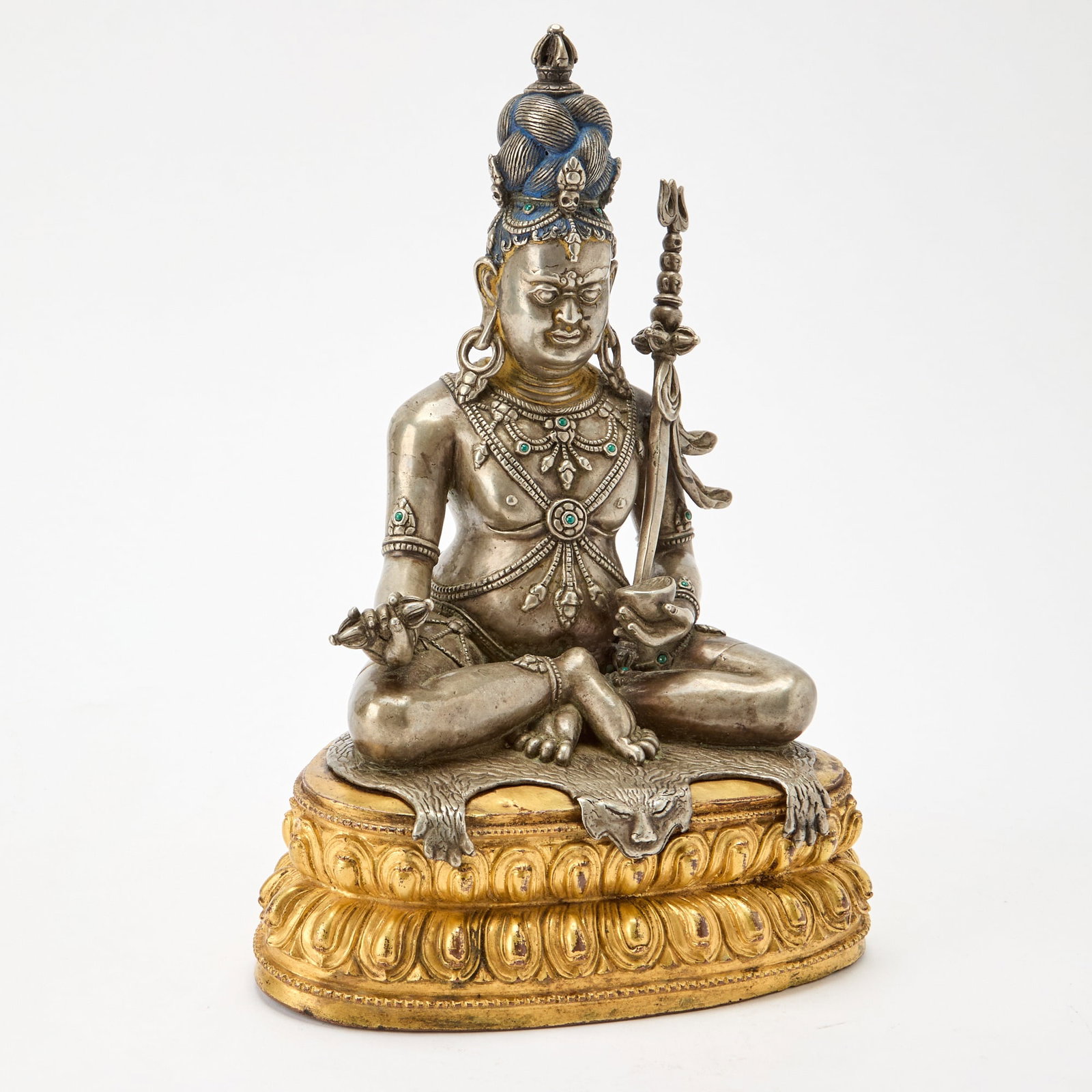 A Large and Rare Tibetan Parcel Gilt Mixed Metal Alloy Figure of Tsangnyon Heruka 18th-19th century: The silvered figure shown with blue-tinted upswept coiffure surmounted by flanged dorje and adorned with ornate jewelry inset with turquoise beads holds a ritual staff, skull cup and vajra while seate