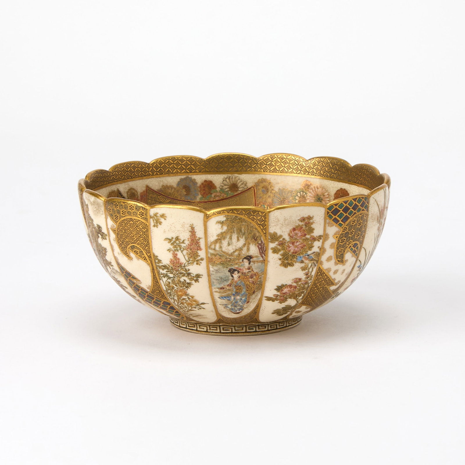 A Japanese Satsuma Earthenware Bowl Hankinzan, Meiji Period: The rounded sides rising to a scalloped rim; decorated with shaped panels depicting figures, floral motifs, and geometric designs, respectively; the interior adorned with figures in an architectural s