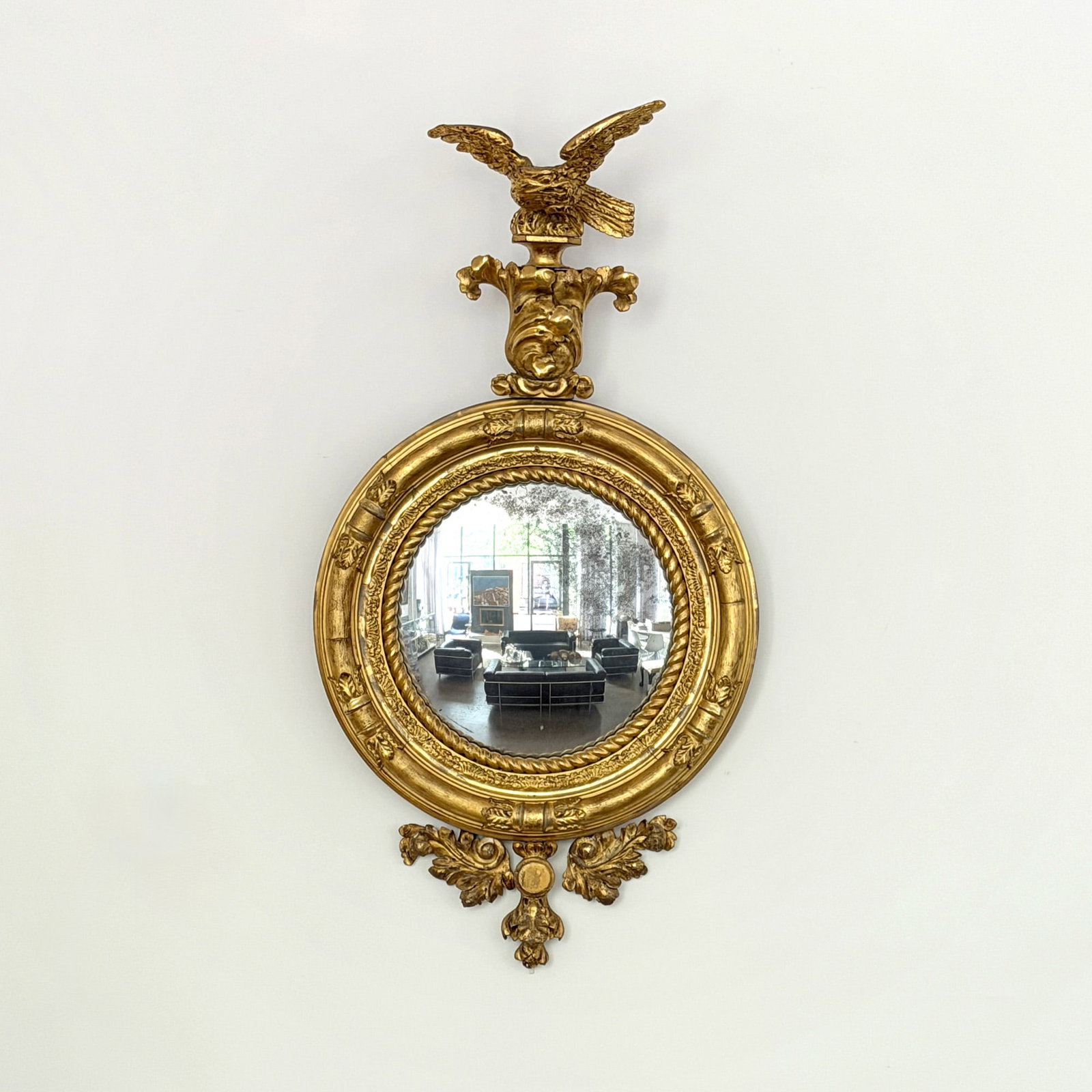 Classical Giltwood Girandole Mirror: Early 19th century The eagle finial on an acanthus plinth above a circular frame with ropetwist liner. Height 54 inches, frame diameter 28 inches. One eagle wing broken and repaired.