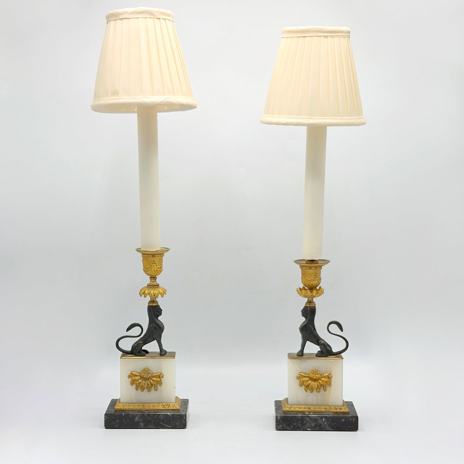 Pair of Empire Style Gilt and Ebonized Bronze and Marble Candlestick Lamps: France, late 19th century Height overall 20 3/4 inches. One with missing center finial piece