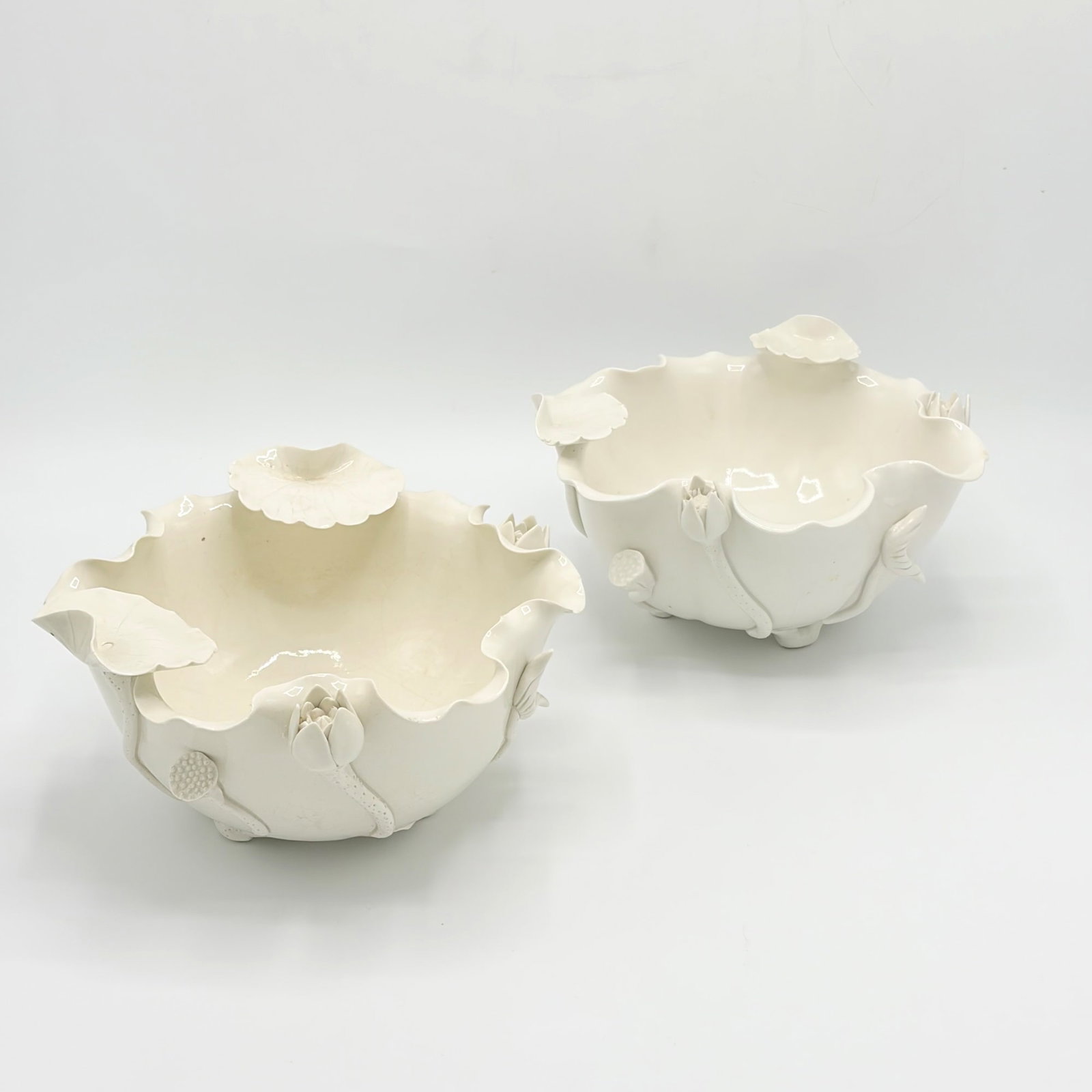 Pair of Chinese Blanc de Chine Porcelain Bowls: Late 19th/early 20th century The bowls with ruffled and lily pad-decorated edges and applied flowers to exterior. Height 4 1/2 inches, diameter 8 1/4 inches. One bowl with hairline cracks to base.