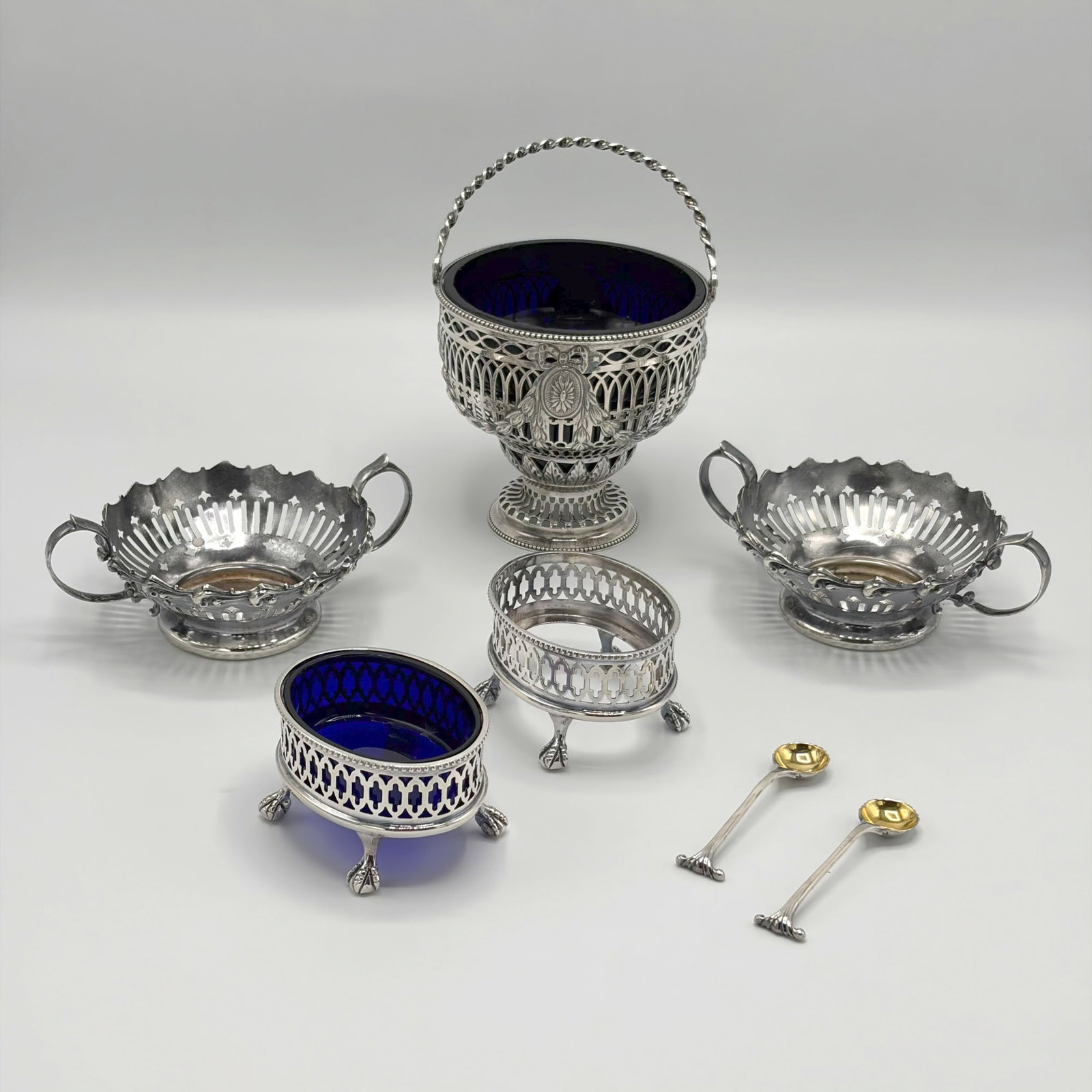 Three English Sterling Silver Reticulated Table Articles: Comprising a sugar bowl marked Charles Aldridge & Henry Green, London, 1774, height to top of handle 6 3/4 inches; and a pair of salts and salt spoons marked Asprey & Co. Ltd., 1988. Together