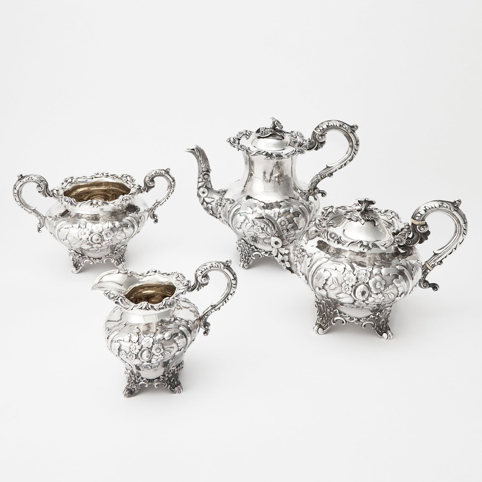Victorian Sterling Silver Tea and Coffee Service: J.E. Terry & Co., London, 1839 Comprising a teapot, coffee pot, height 9 inches (23 cm), cream jug and a sugar bowl, each baluster-form body chased with flowers and leaves, raised on foliate