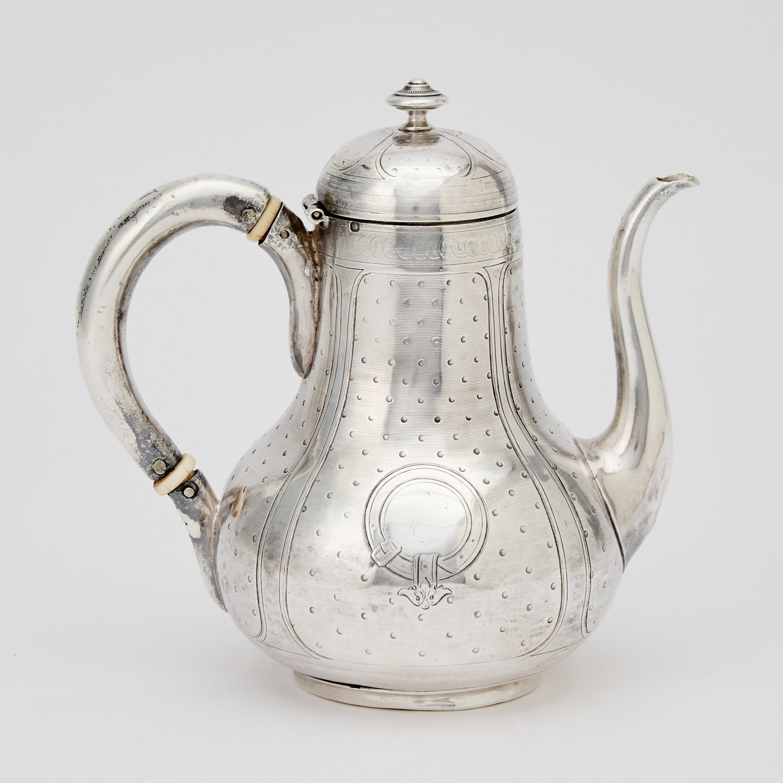 French Silver Bachelor's Teapot: Emile Hugo, mid 19th century Pear-form with overall engine turned decoration, with a scroll spout, the hinged cover with a button finial. Height 5 1/2 inches, approximately 7 ounces, all in. This