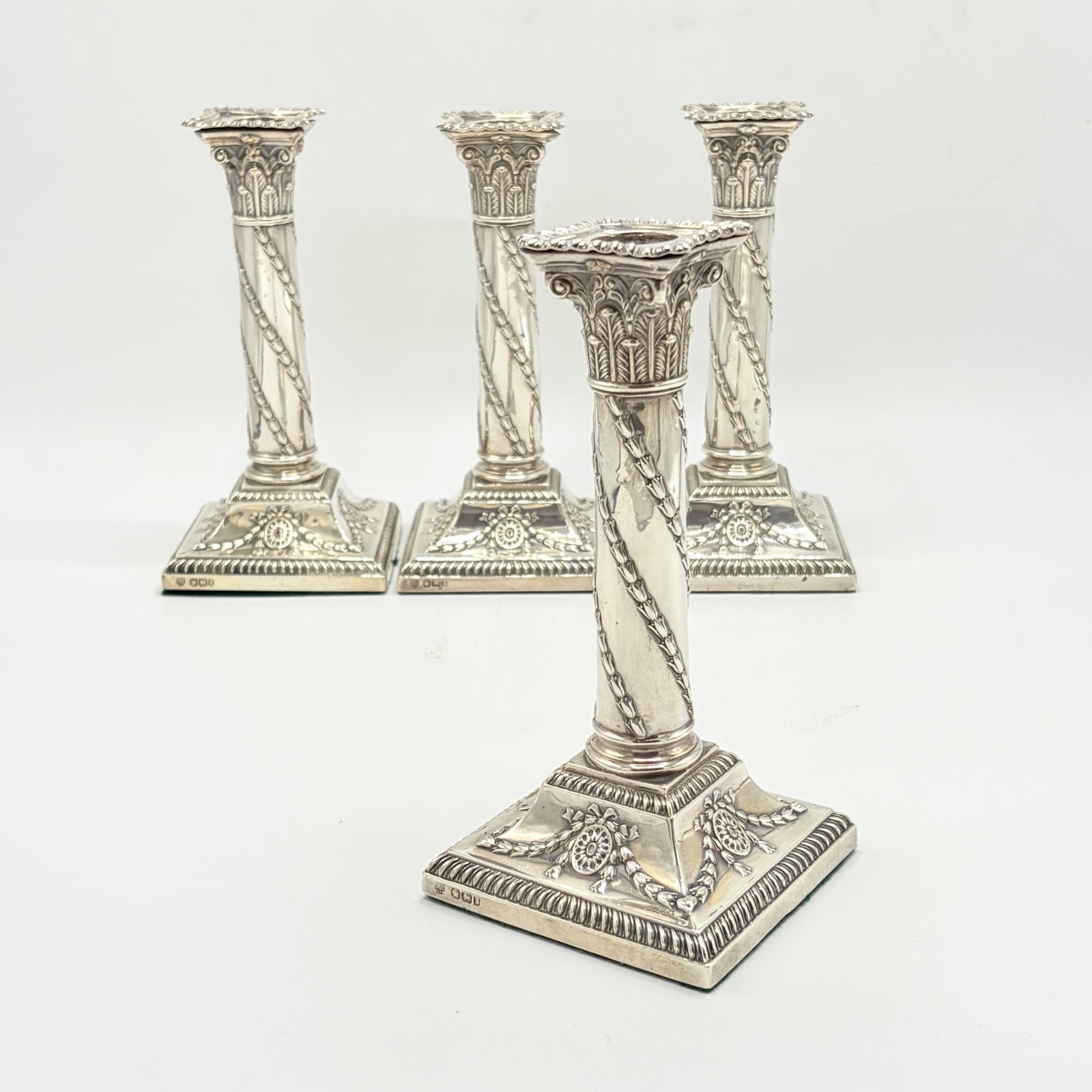Set of Four Victorian Sterling Silver Candlesticks: Hawksworth, Eyre & Co. Ltd., Sheffield, 1894 Each columnar stem with spiral bell flowers, on a square base with rosettes hung with swags and gadrooned border. Height 7 1/2 inches, weighted.