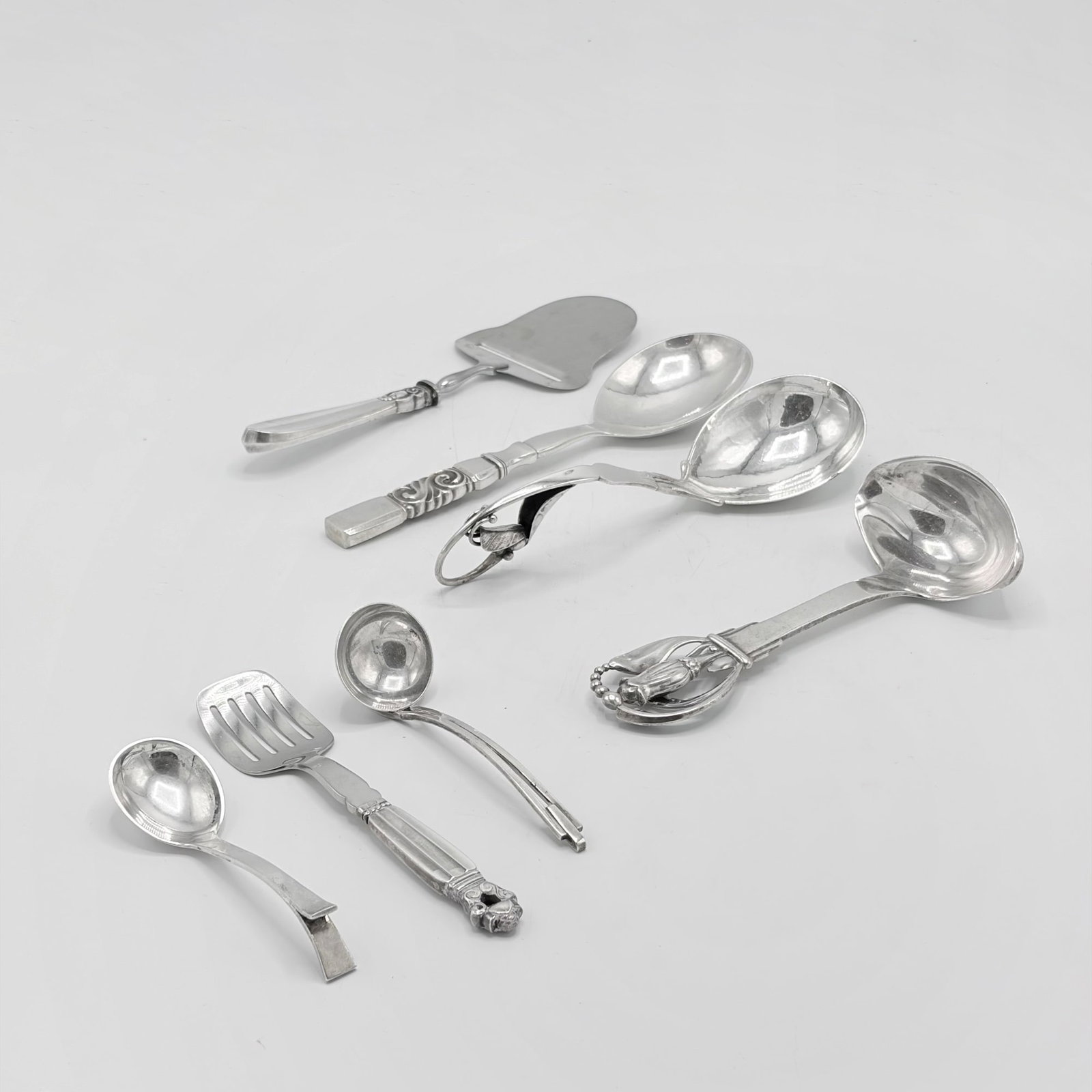 Group of Eight Danish Sterling Silver Serving Pieces: 20th Century Including a gravy ladle with stylized tulip finial marked W. & S. Sorenson, length 7 inches; Poul Frigast "Princess Fuchsia" pattern cheese plane, four Georg Jensen serving pieces, et