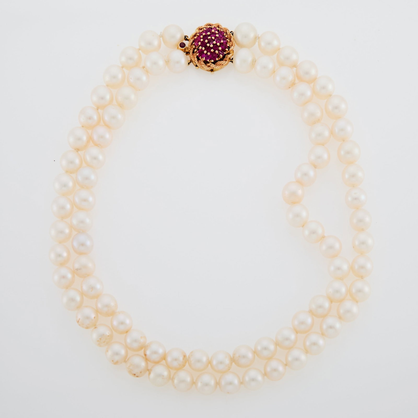 Double Strand Freshwater Pearl Necklace with Gold and Ruby Clasp: Pearls ap. 10.6 to 10.0 mm., round rubies, one ruby missing. Length 17 1/4 inches. Tests as 14 kt. Pearls: slightly creamy white, dimples, good luster. Rubies: medium slightly purplish pinkish red,
