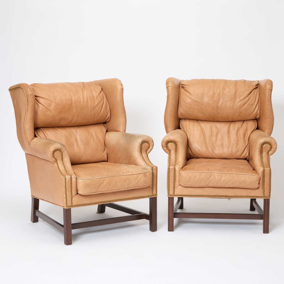 Pair of George III Style Mahogany and Leather Upholstered Wing Chairs: Late 20th century Made by Leather Center. Height 42 inches, width 32 inches, depth 31 inches. worn and faded leather