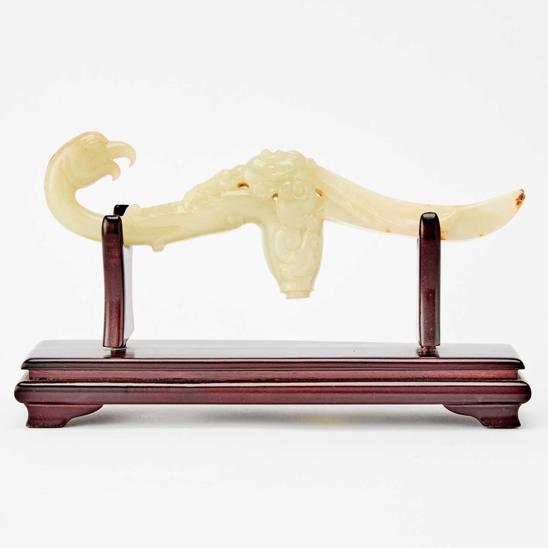A Chinese Carved Celadon Jade Handle Qing Dynasty: Carved as a bird with a curving body; the stone with russet inclusions. (Length 9 1/4 inches)