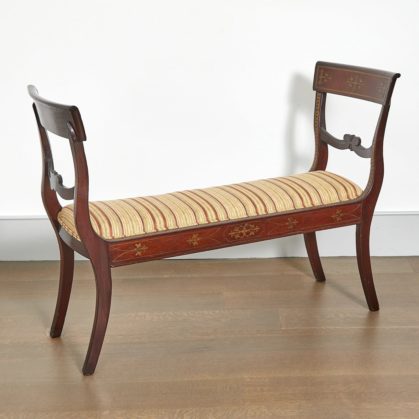 Regency Brass Inlaid Mahogany Window Bench: Early 19th century Of canted form, the rectangular seat covered in striped upholstery on curved legs. Height 33 inches, width 48 inches; depth 19 inches, seat height 18 inches.