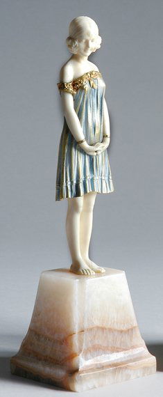 Cold Painted Bronze and Ivory Figure: Cold Painted Bronze and Ivory Figure After a model by Demetre Chiparus, circa 1925 Modeled as a young female in a gold and blue dress, with slightly bowed head and hands clasped before her, on a tape