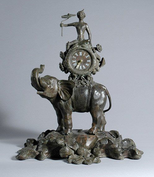 Louis XV Style Patinated-Bronze Animalier Clock: Louis XV Style Patinated-Bronze Animalier Clock Modeled as a striding elephant surmounted by a clock case surmounted by a turbaned monkey holding a parasol, on a naturalistic foliate decorated base.