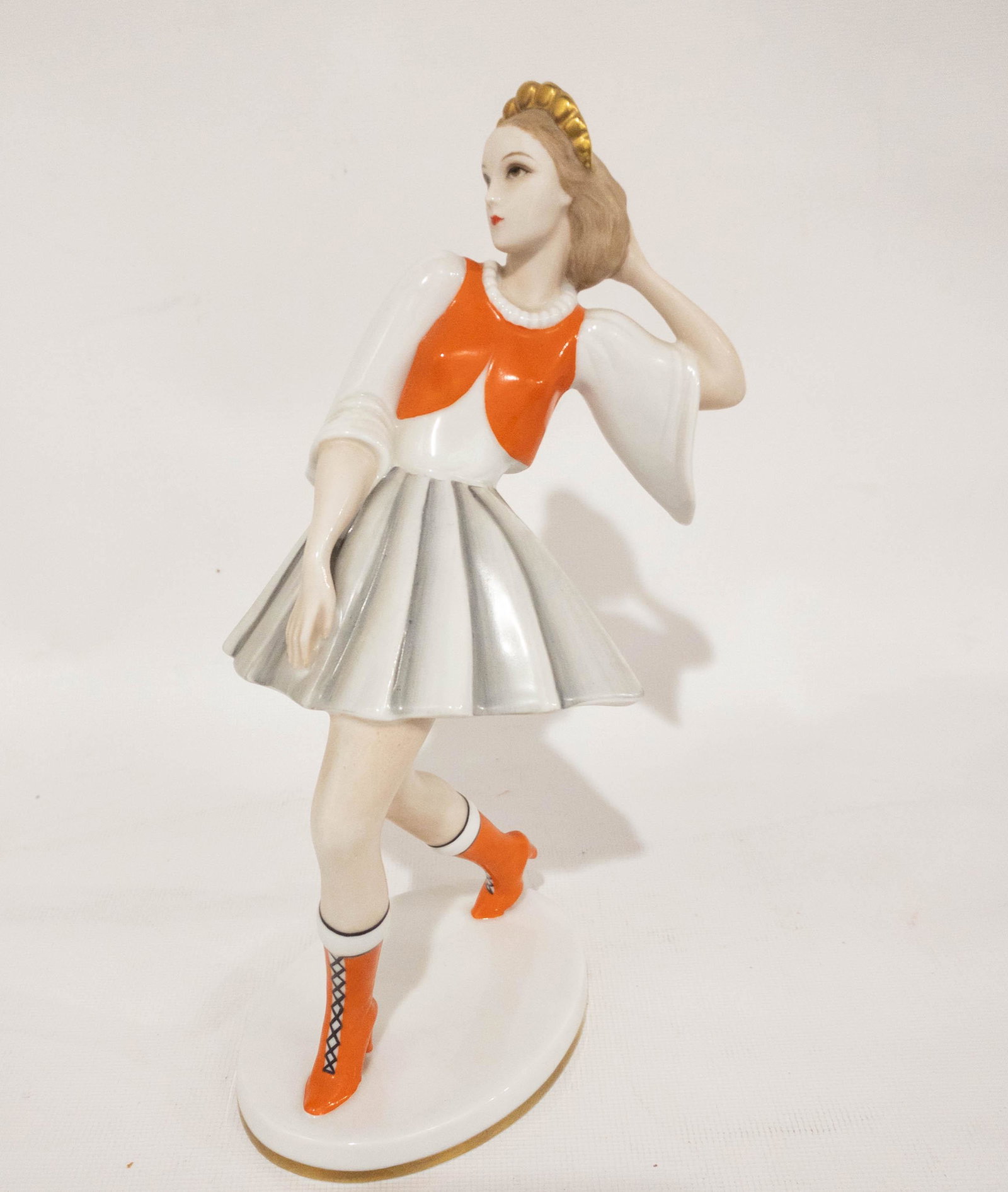 HC & Schlaggenwald Czechoslovakia Model Figurine: A porcelain figurine by HC & Schlaggenwald, Czechoslovakian model in orange lace up boots, a white dress, orange vest and gold tiara. 9" high x 4" long x 3" wide