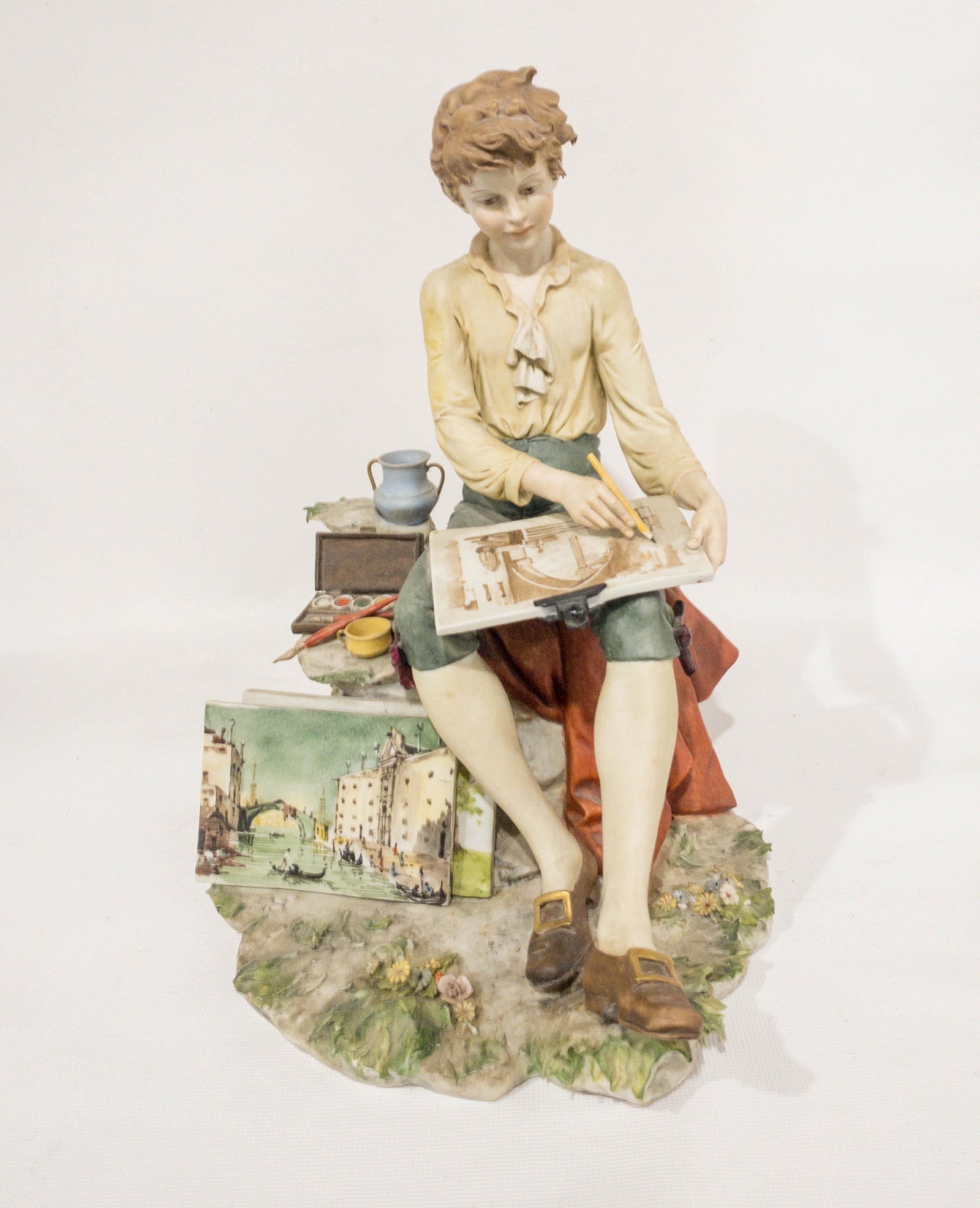 Benacchio Porcelain Figurine Statue Boy Painting Italy: A highly detailed and colorful statue of a boy painting scenes in Italy. Signed: Benacchio. 11.5" high.