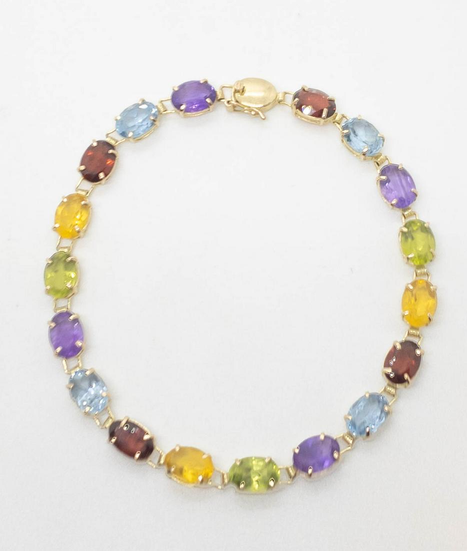 14k Yellow Gold Multi Synthetic Gemstone Bracelet: 14k yellow gold multi-colored gemstone bracelet including topaz, ruby, amethyst, citrine, garnet and aquamarine prong set synthetic stones measuring 7mm x 4.5mm each. 7" long. Marked: 14k, 585. Weight