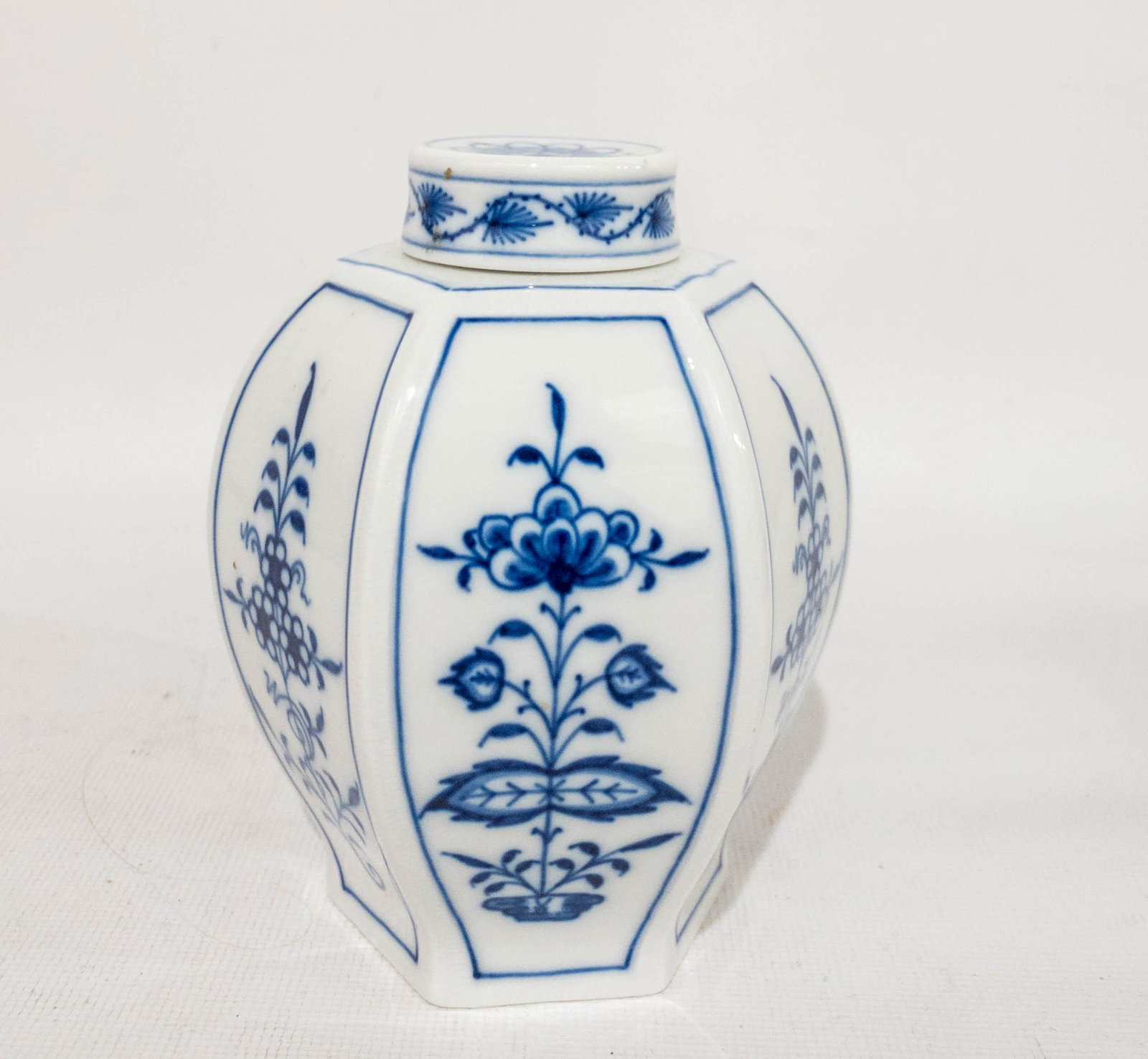 Antique Meissen Blue & White Lidded Tea Jar: Antique Meissen blue & white lidded tea jar with 6 panel each featuring a floral design. Marked on bottom. 5" high, 4" diameter at widest point.