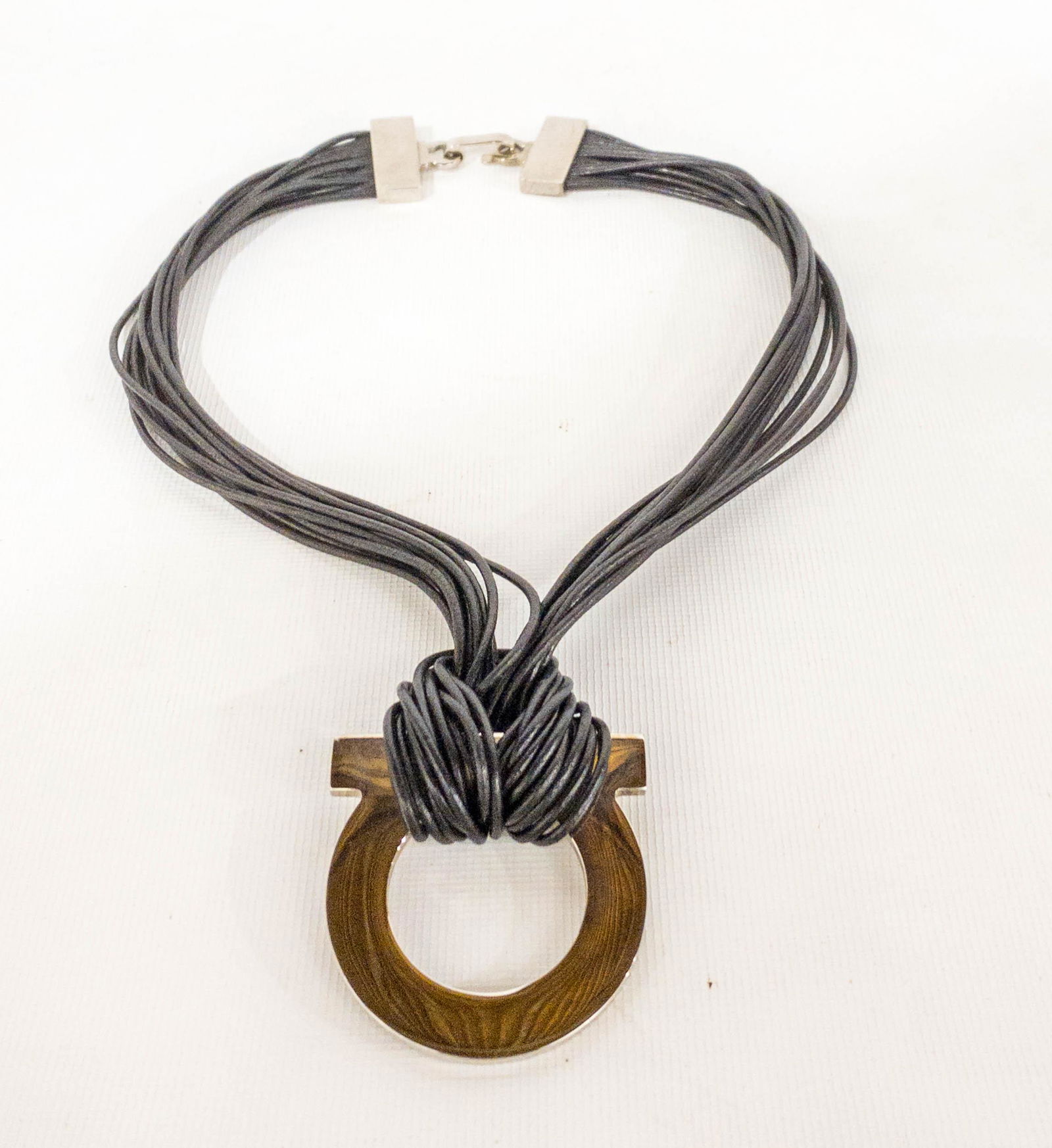 Salvatore Ferragamo Leather & Silvertone Gancini: Salvatore Ferragamo necklace featuring a large, 2.25" x 2.25", gancini pendant hanging on 12 round leather bands. Hook closure. Marked: Ferragamo, Made in Italy. 20" long.