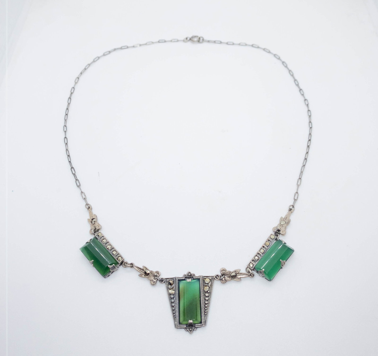 Art Deco Sterling Silver Green Glass & Marcasite: Art Deco sterling silver necklace featuring green glass and marcasite hanging on an oval cable link chain. 16" long. Marked: Sterling.