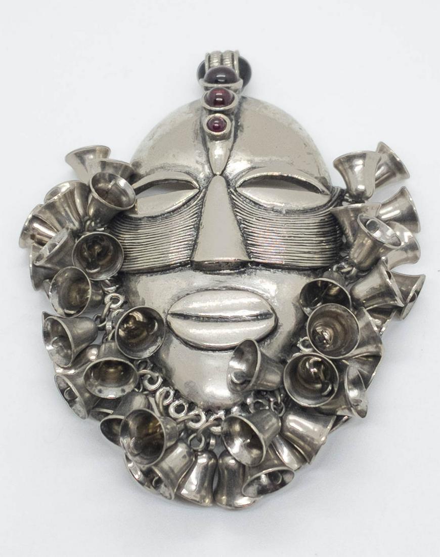 Vintage Tribal Mask & Bell Brooch Faux Ruby Cabochon: Exception costume pendant or brooch featuring a tribal mask surrounded in bells and adorned with faux ruby cabochons. 4" high x 3" wide.