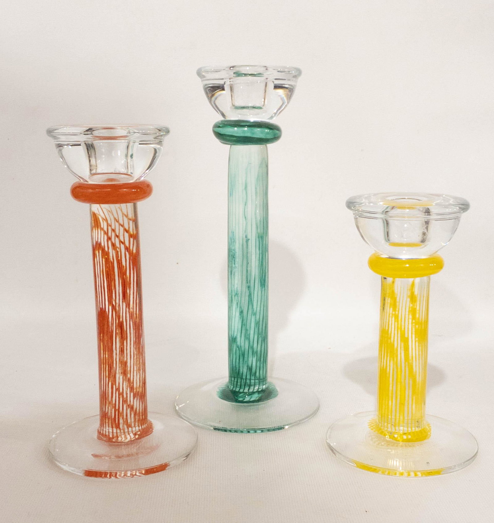 Kosta Boda Kjell Engman Glass Candle Sticks Set of 3: 3 glass candlesticks from Kosta Boda by Kjell Engman in green, 9" high, red, 7.75" high, and yellow, 6.25" high. Each is signed: Kosta Boda, Engman.