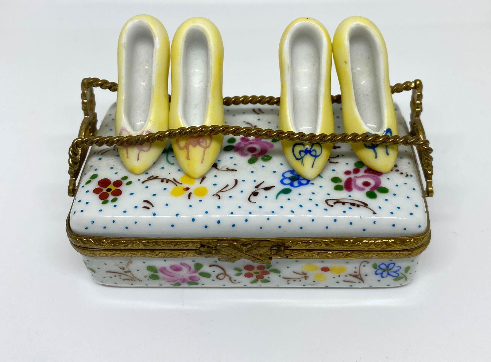 Limoges France Peint Main Shoe Trinket Box: Vintage porcelain trinket box from Limoges, France in a floral and polkadot design with 2 pair of shoes on top. Marked: Peint Main, Limoges, France. .5" high x 2.5" long x 1.5" wide.