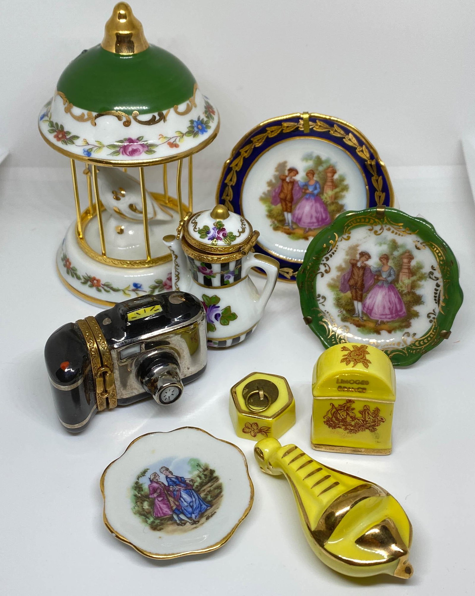 Limoges France Porcelain Collection Plates, Trinket: A collection of 9 porcelain Limoges pieces including 3 miniature plates ranging in size from 1.75" - 2.5" diameter, a teapot trinket box, 2" high, a camera trinket box 2" long x 1" high, and 3 yellow 