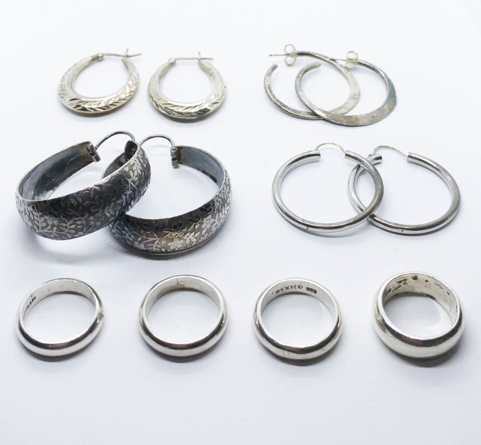 A lot of Sterling Silver Hoop Earrings & Band Rings: A lot of sterling silver jewelry including 4 pair of hoop earrings, 1.25-1.5" long and 4 band rings, 2 are size 5 and 4.5mm wide, 1 is a size 5.75 and is 4.2mm wide, and the 4th is s doxr 6 smf 7.5mm 