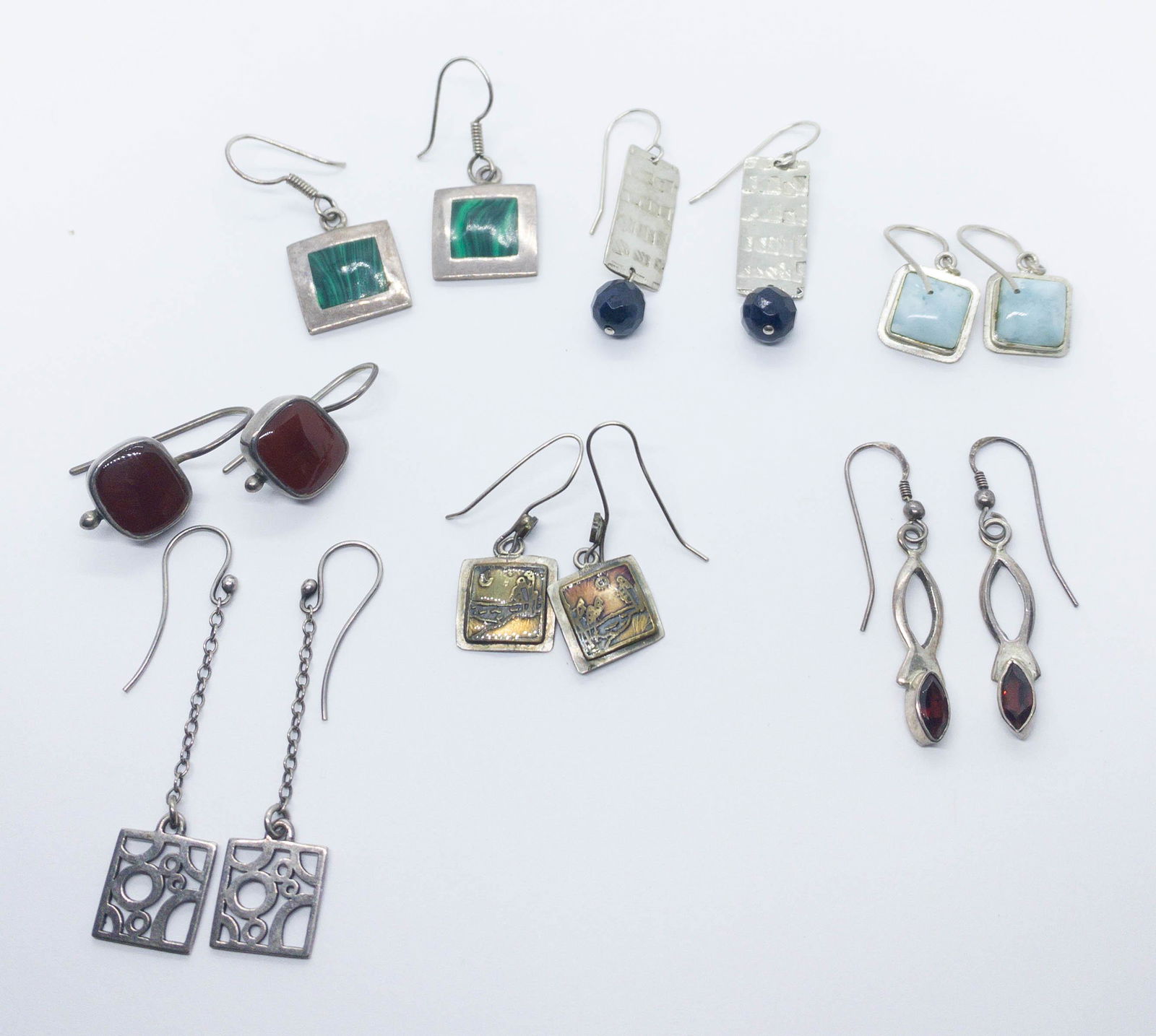 7 Sterling Earrings Carnelian, Malachite, Garnet: A lot of 7 pairs of sterling silver pierced earrings all on wired hooks boasting, garnet, malachite, crystal, larimar, and carnelian. Sizes range from 1" to 1.5" long. Total weight: 35. grams.